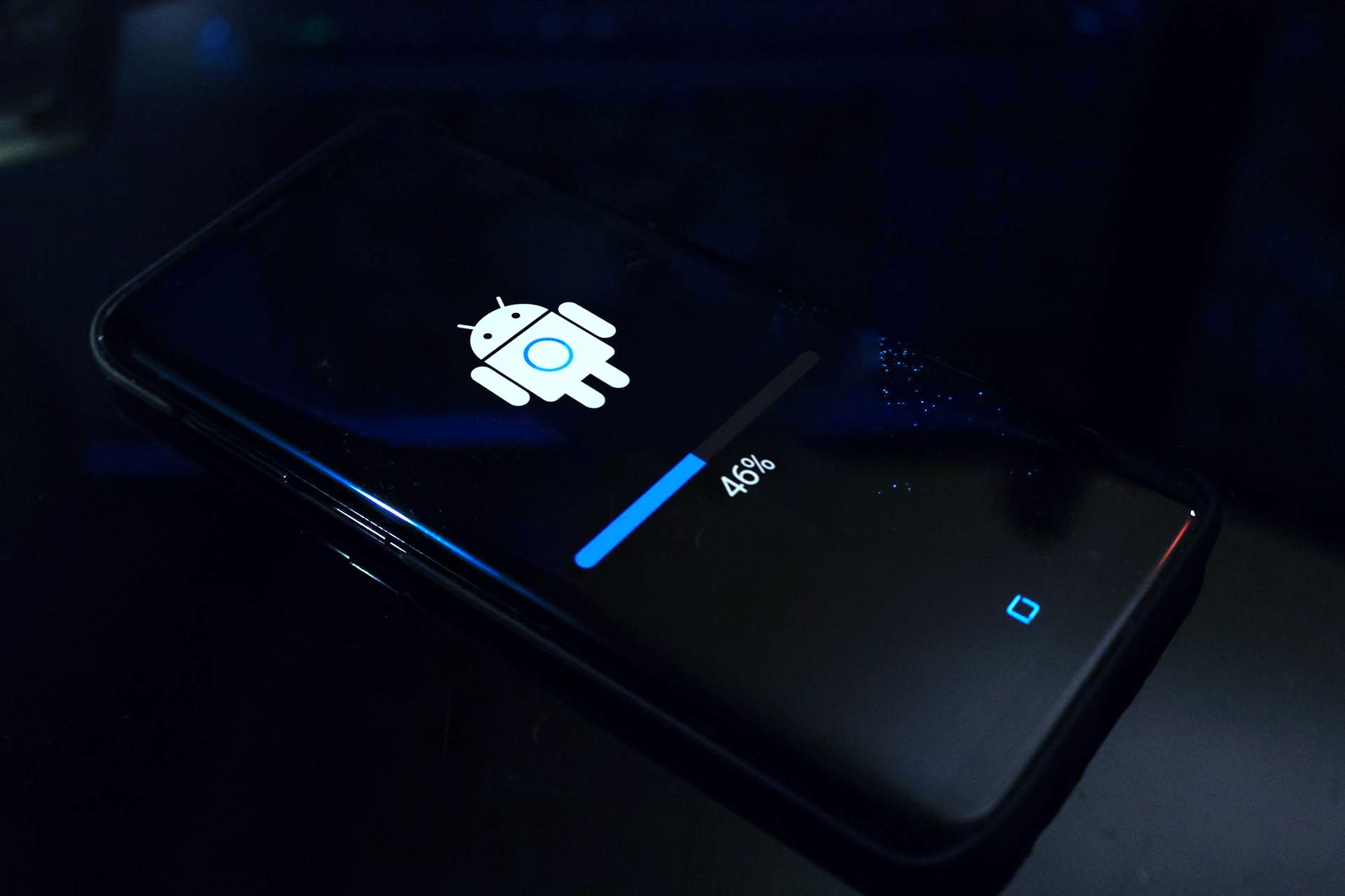 An Android smartphone lying on a surface, displaying an update screen with an Android robot icon and a progress bar indicating 46% completion.