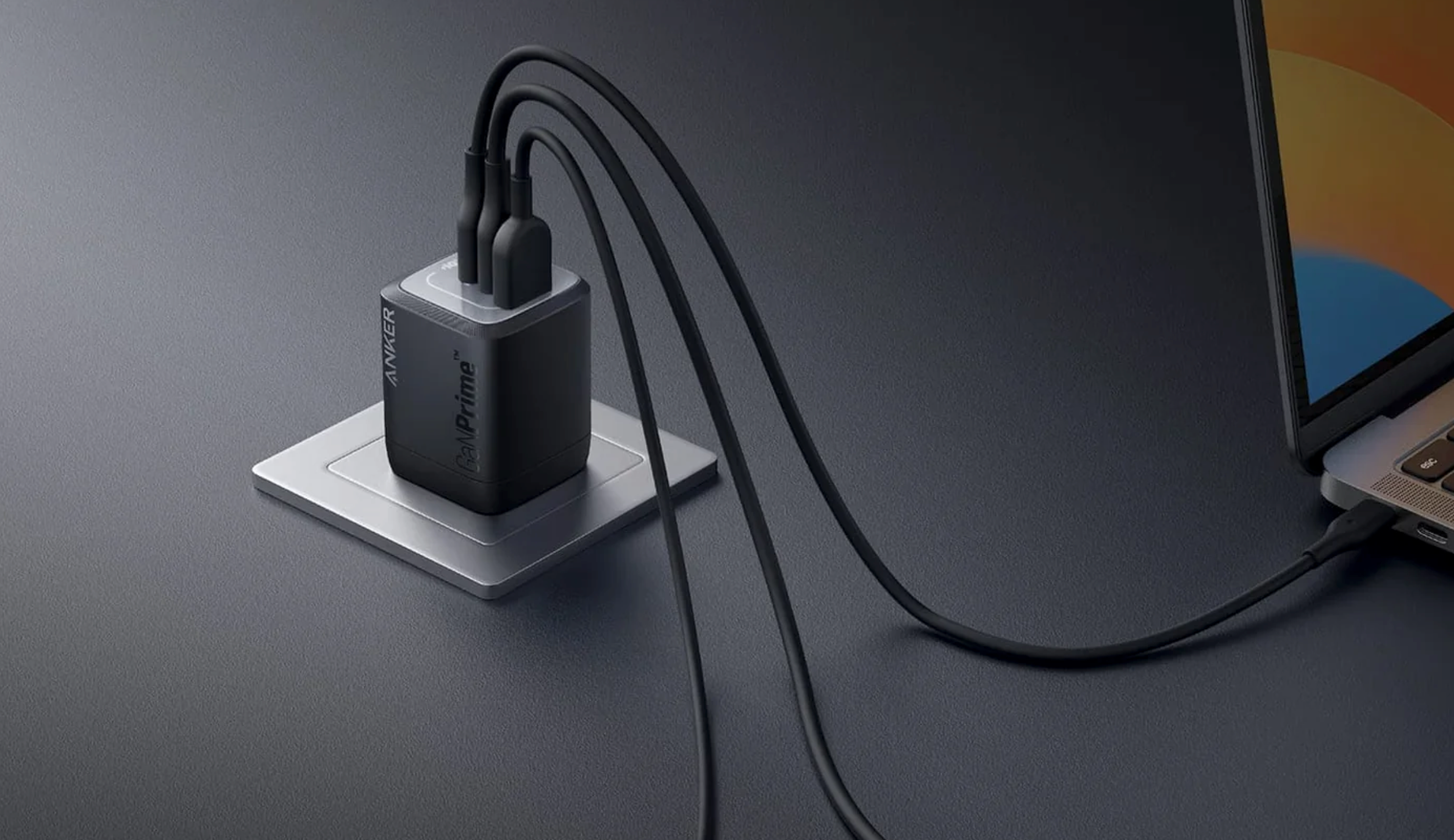 Anker USB-C charger plugged into an outlet on a gray des