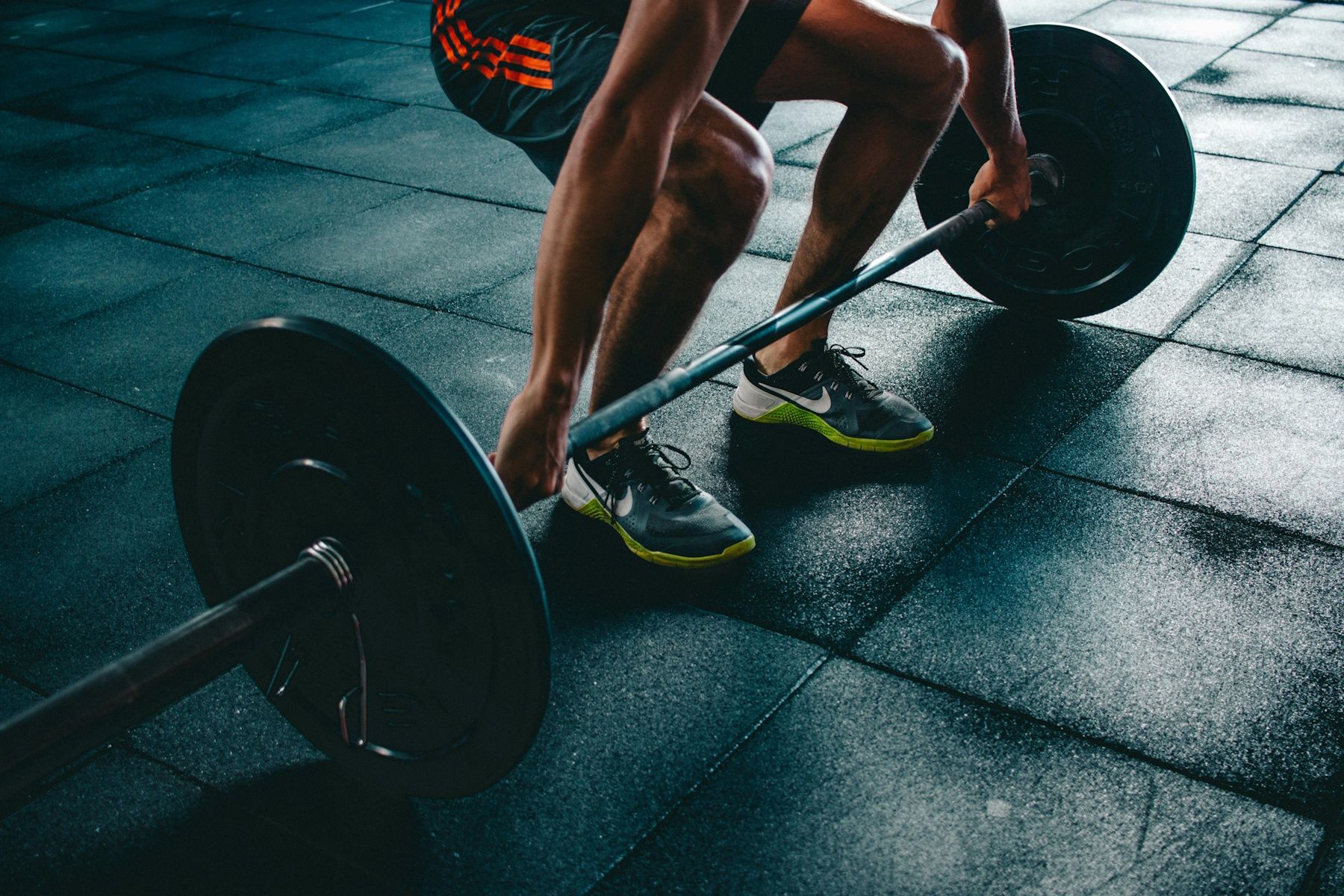 man wearing nike shoes lifting a barbell