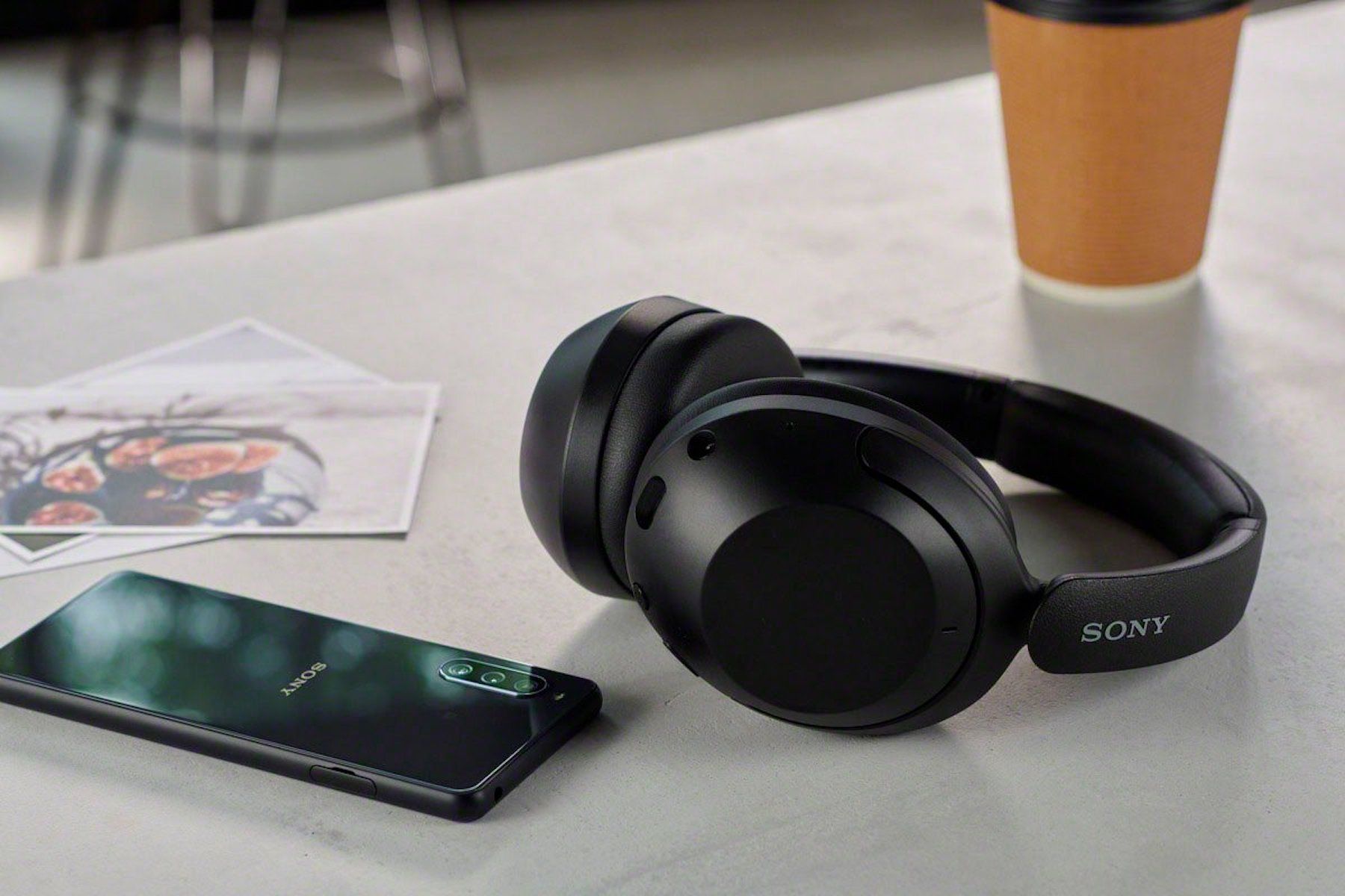 black-sony-over-the-ear-headphones-on-table-next-to-coffee-and-sony-phone