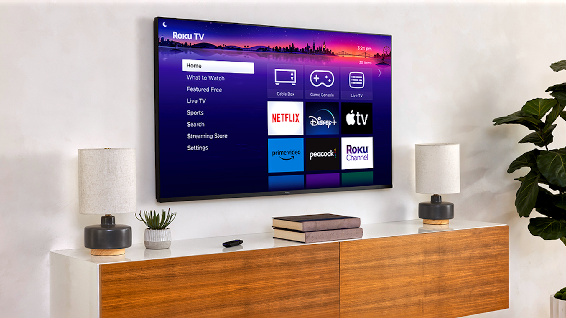 A TV with the Roku homescreen is mounted to a wall above walnut media cabinet