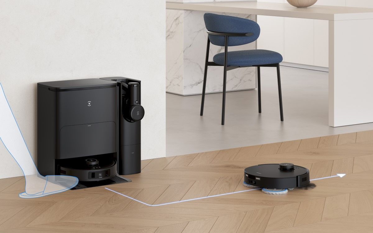 A cartoon foot activates a black robot vacuum