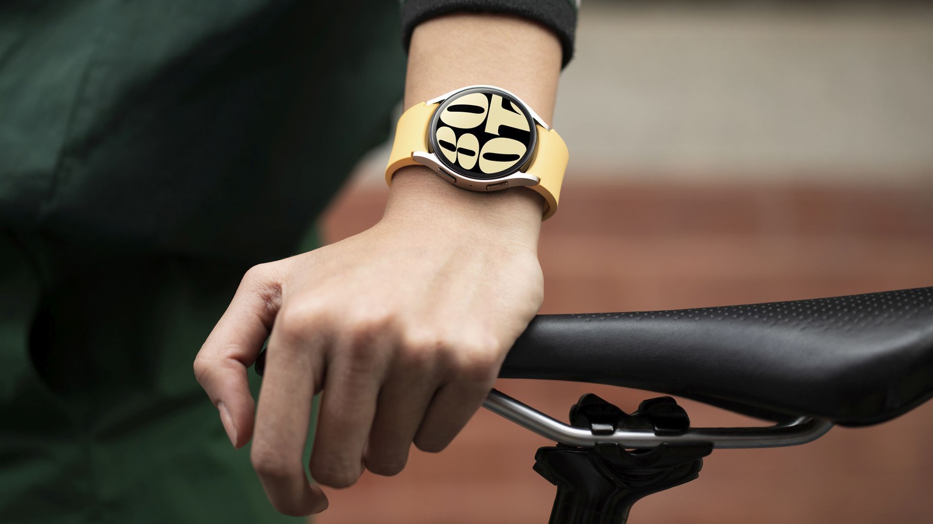 A person wearing a Samsung Galaxy Watch 6 in gold resting their hand on a bicycle seat