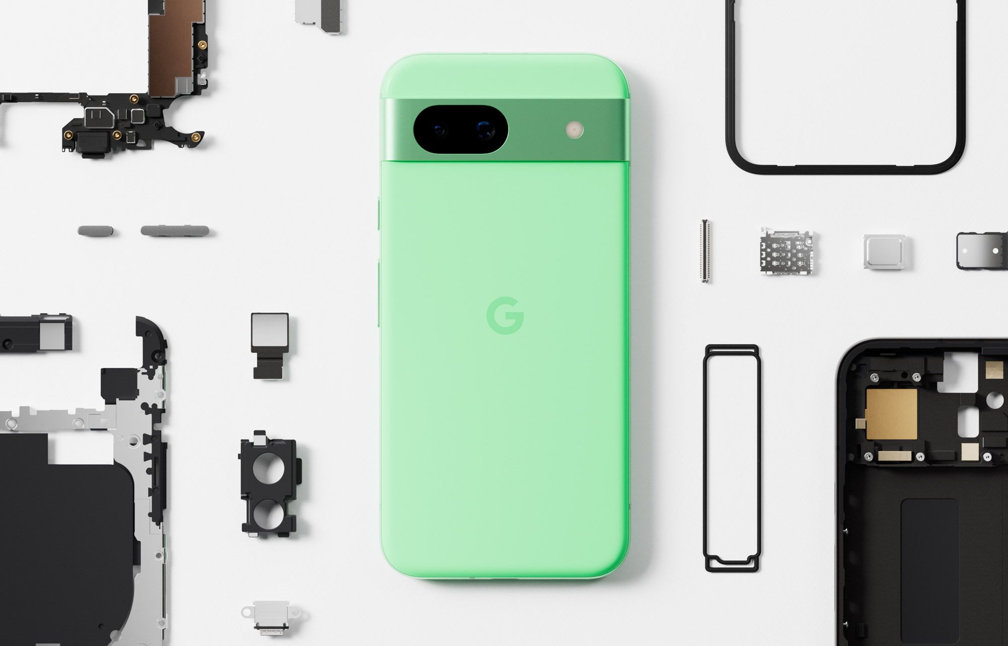 The green Pixel 8a next to its internal parts on a table.