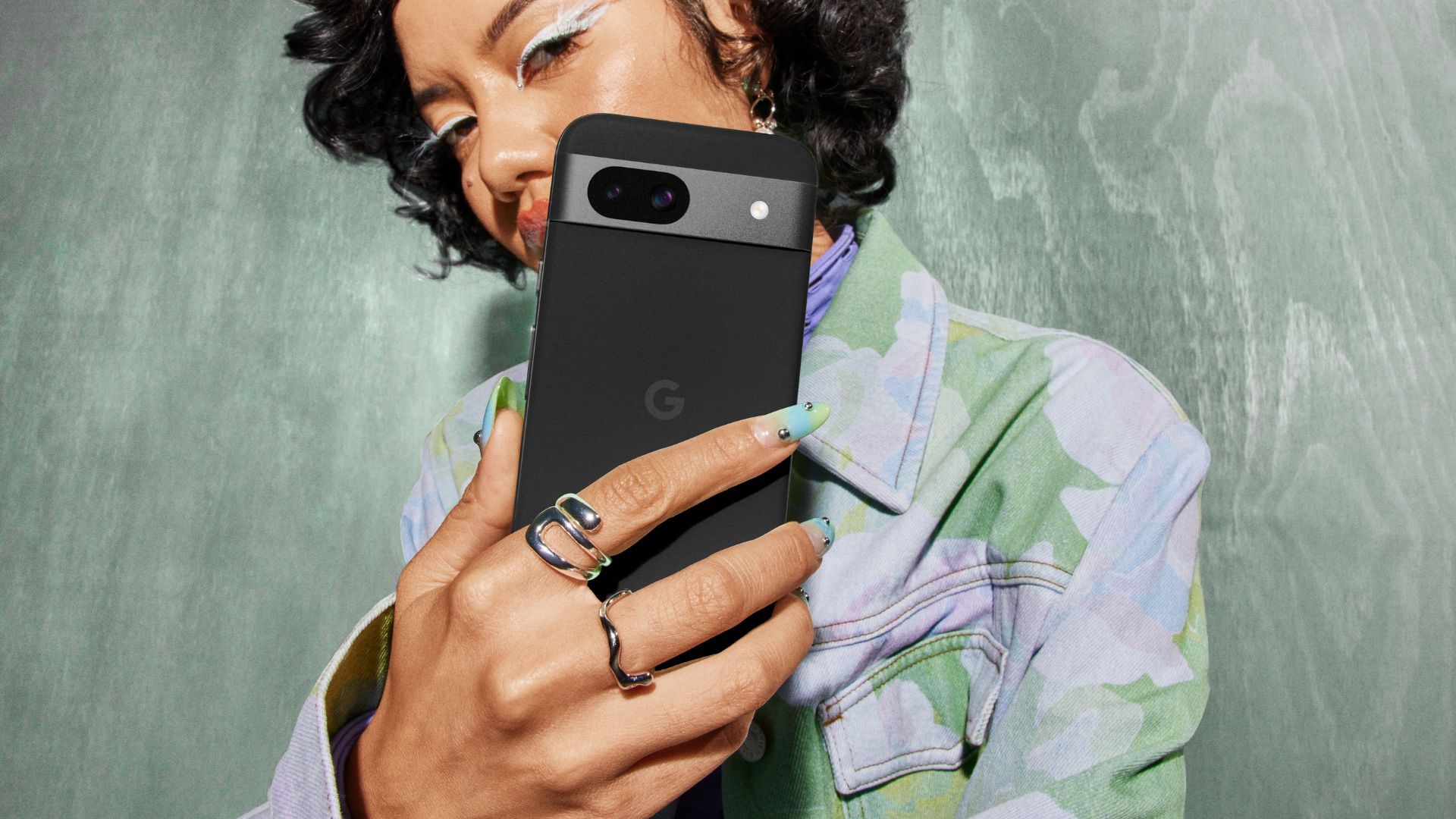 Google Pixel 8a in black held in hands showing off the camera visor and color