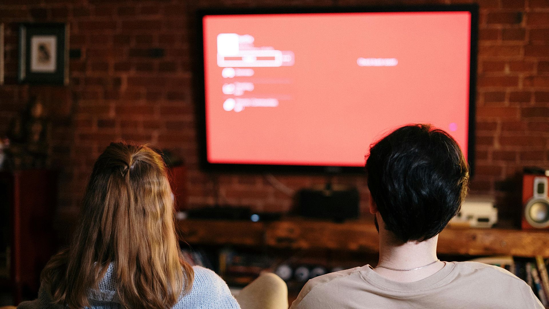 Two people sitting on a couch watching TV