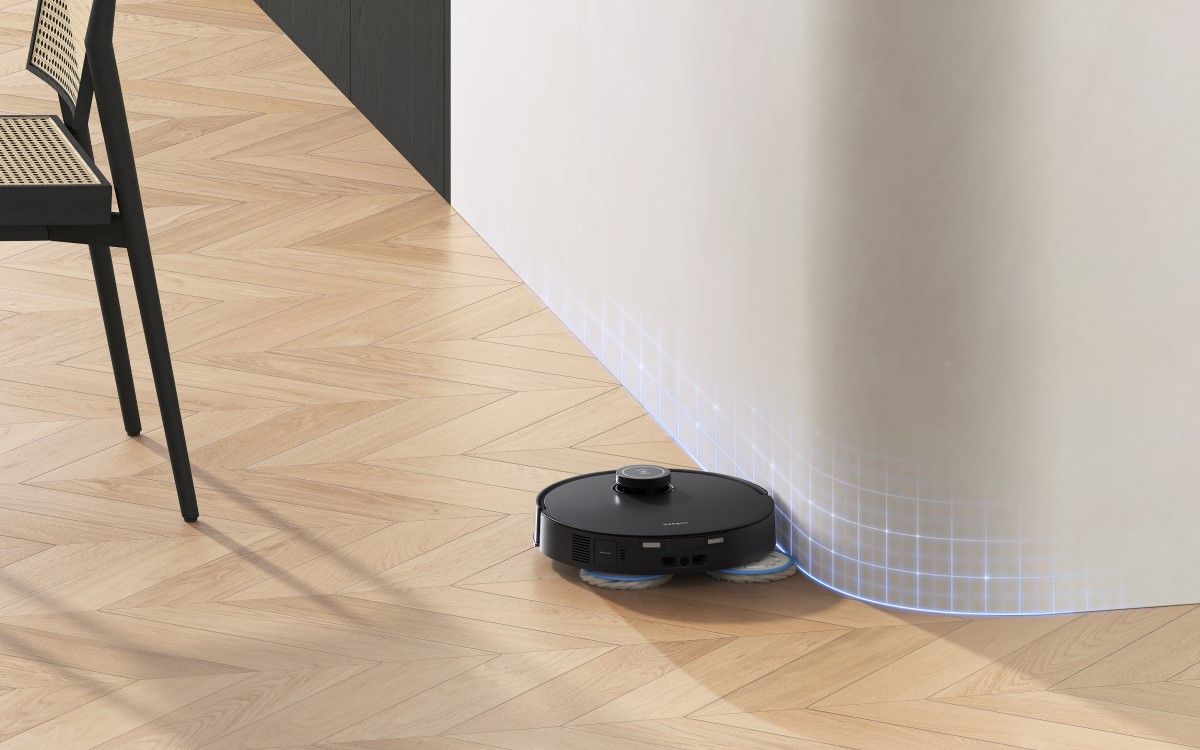 A black robot vacuum mops a curved white wall