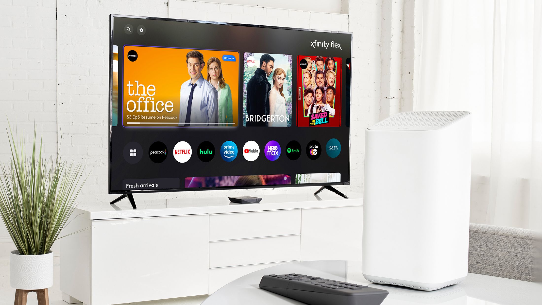 A television with the Xfinity Flex homescreen with a remote and gateway in the foreground