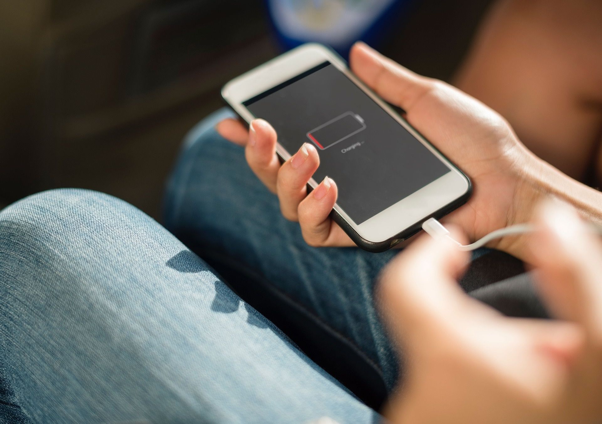 A person sitting with low battery icon displayed on phone screen