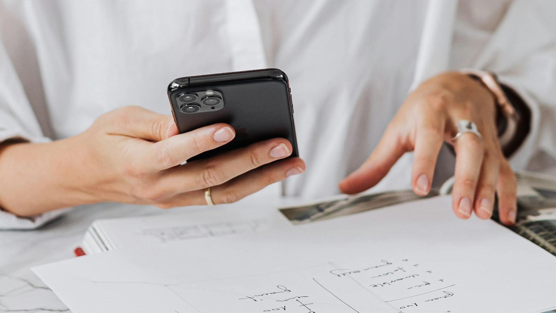 A person in a white shirt holding an iPhone