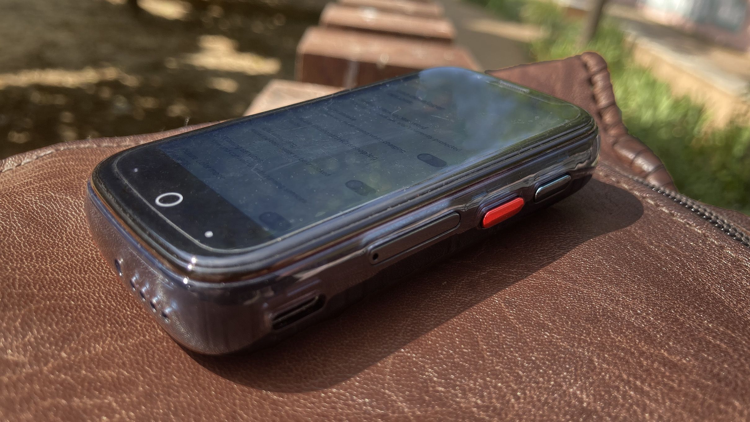 The Unihertz Jelly Star sitting flat on a leather pouch with as view of its buttons, SIM slot, USB port, and lower microphone port