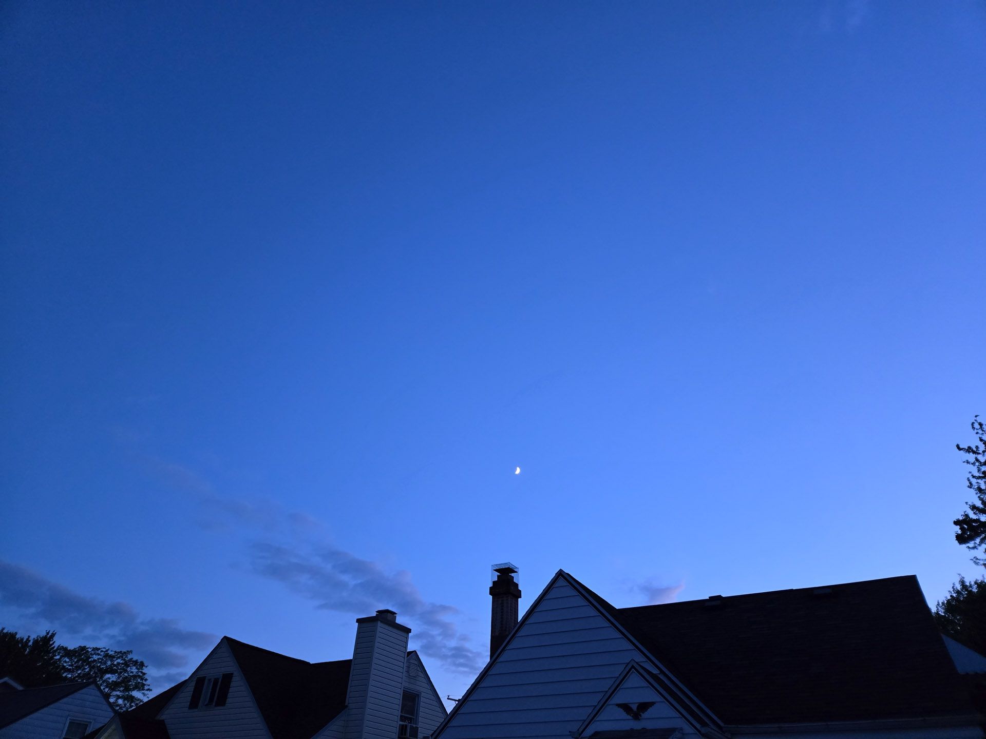 A photo of the sky at dusk with the moon shown.