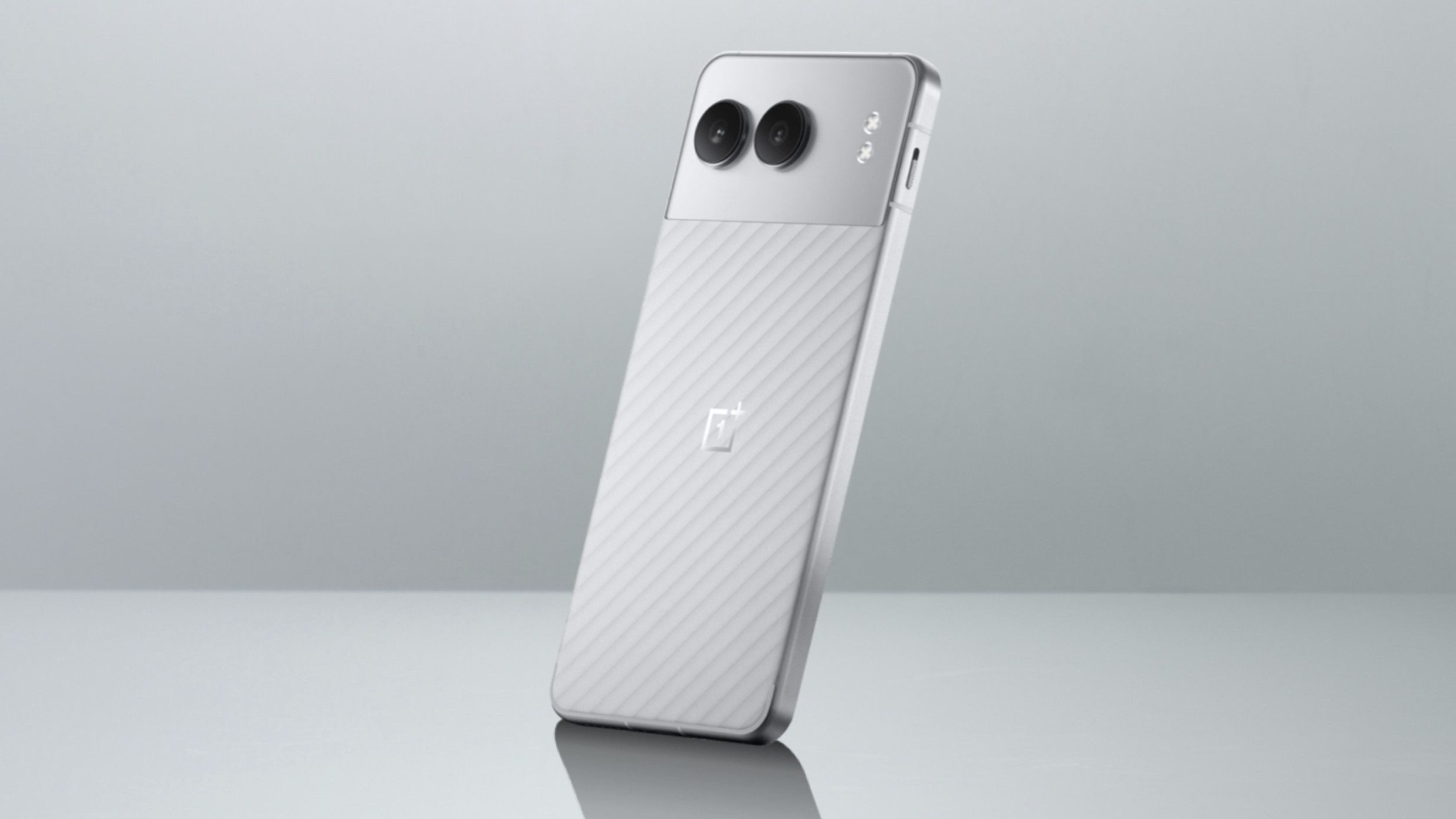 the rear of a silver colored oneplus nord 4 smartphone on a reflective surface 