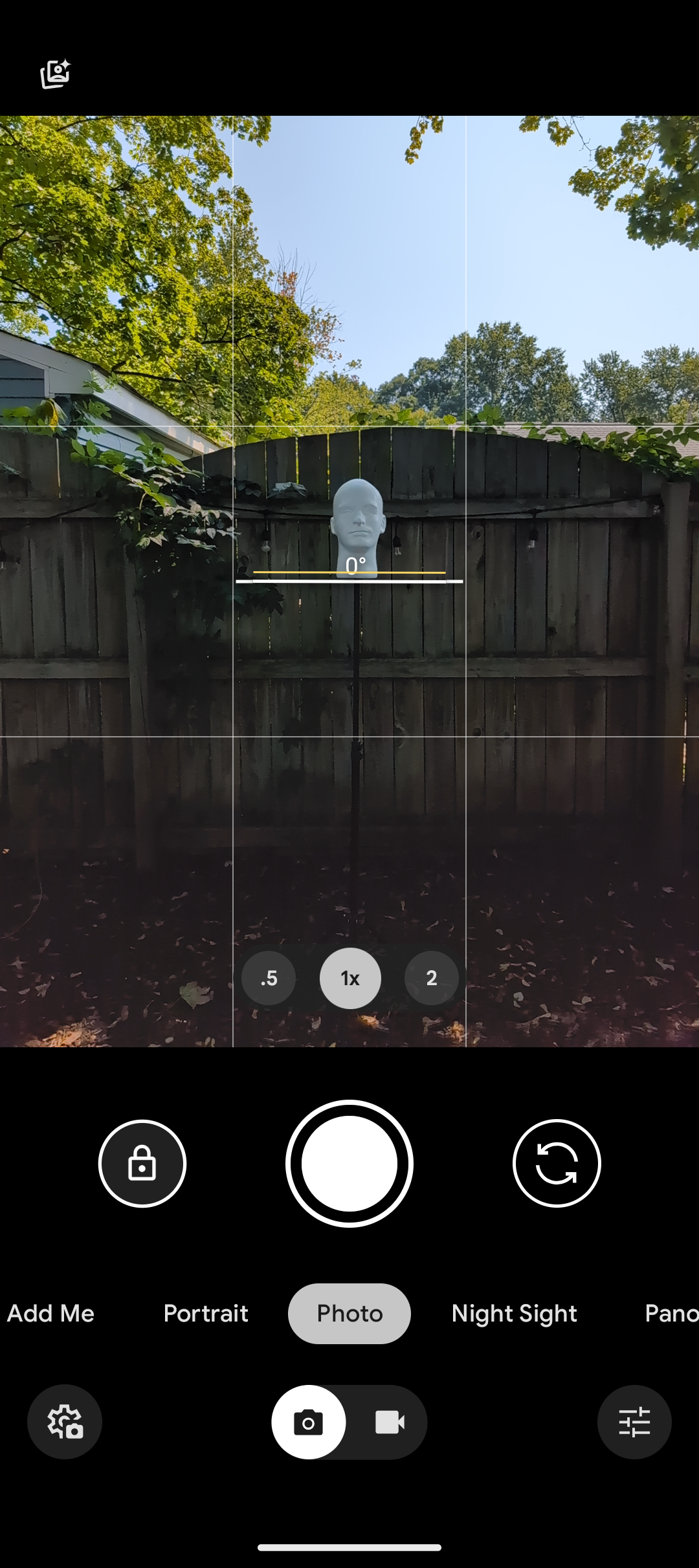 pixel 9 camera viewfinder showing mannequin head in front of garden fence