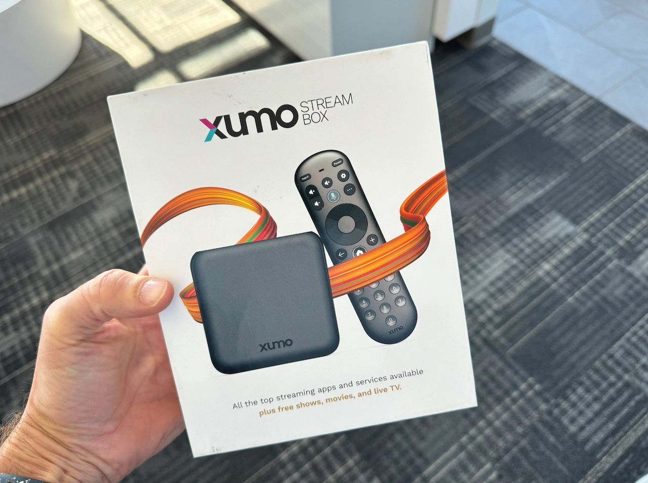 A hand holding an Xumo Stream box