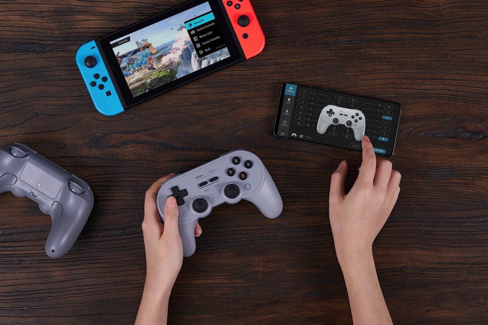 8bitdo Bluetooth controller in-hand alongside Nintendo Switch and Android phone