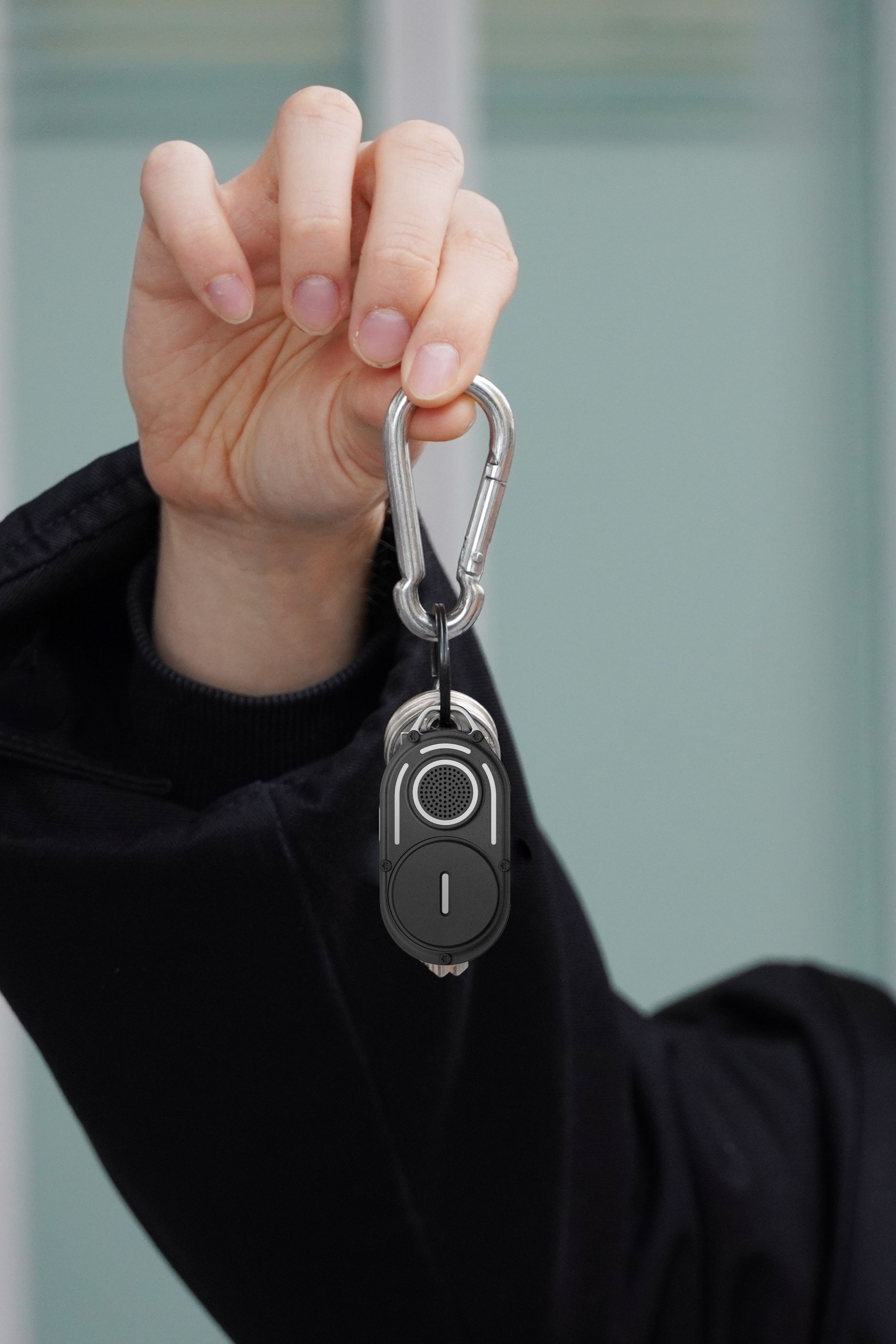 A person holding the AirNotch Pro Bluetooth tracker hanging from a carabiner