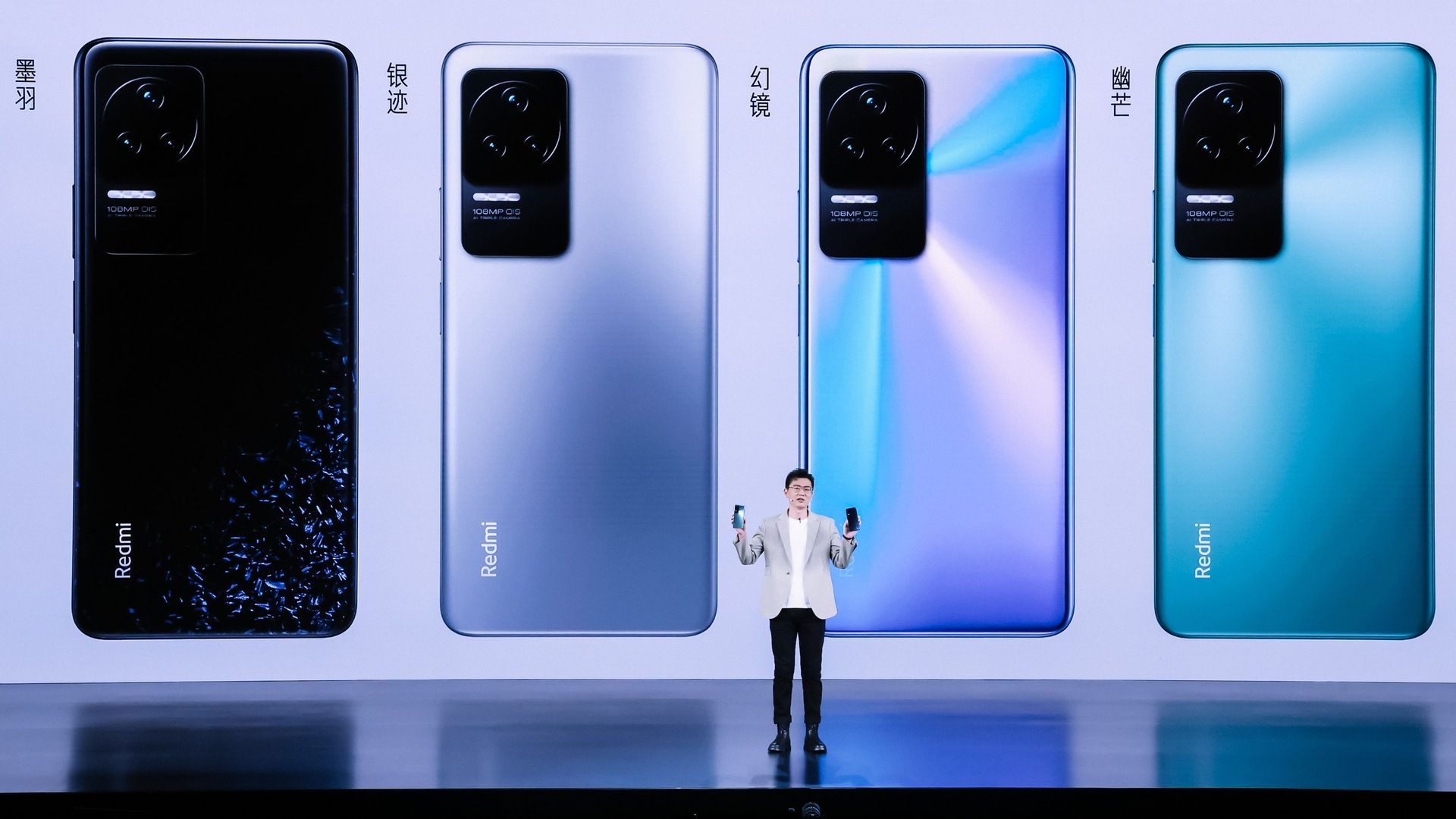 A Xiaomi executive standing in front of four floor-to-ceiling renders of the Redmi K50 Pro