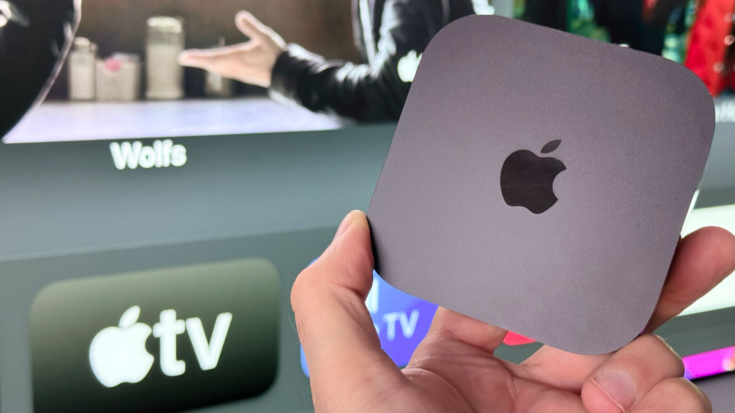 Apple TV 4K being held up in front of a TV screen