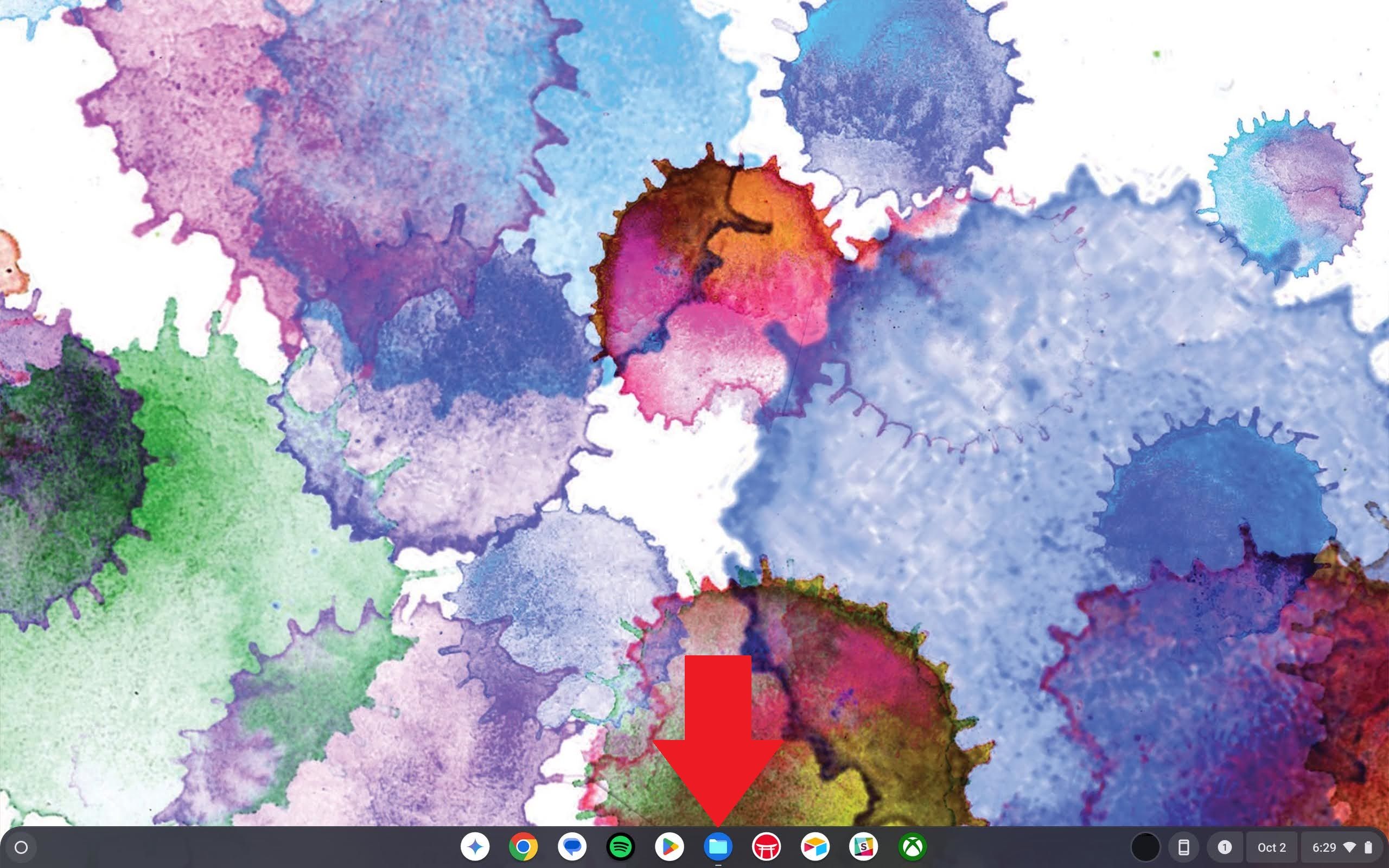 A Chromebook home screen with a red arrow pointing to the Files app icon in the Shelf