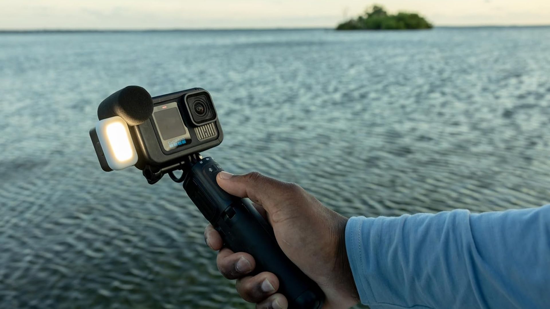 A hand holds the GoPro Hero 13 Black Creator Edition with the ocean in the background.