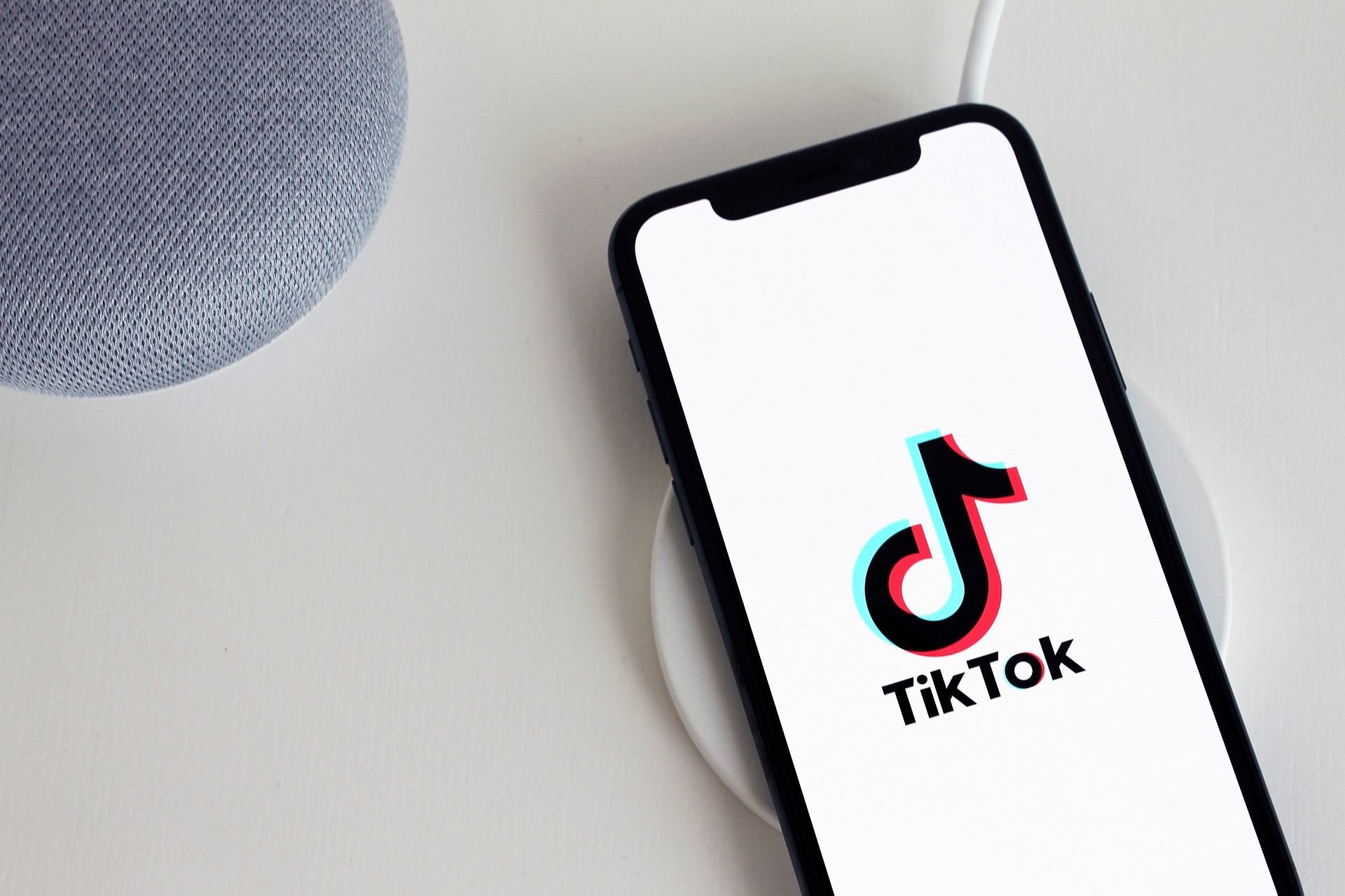 The TikTok app open on an iPhone next to a Google Nest speaker.