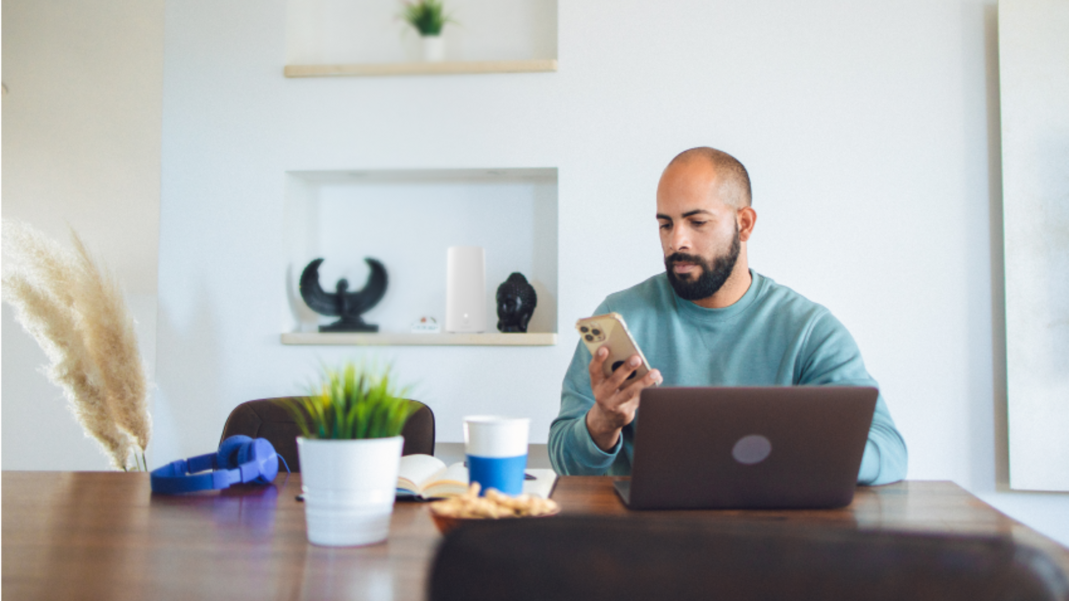 Person on phone using laptop at desk 