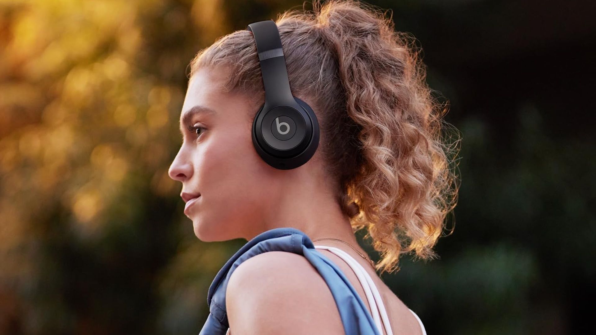 A woman wears a pair of black Beats Solo 4 headphones.