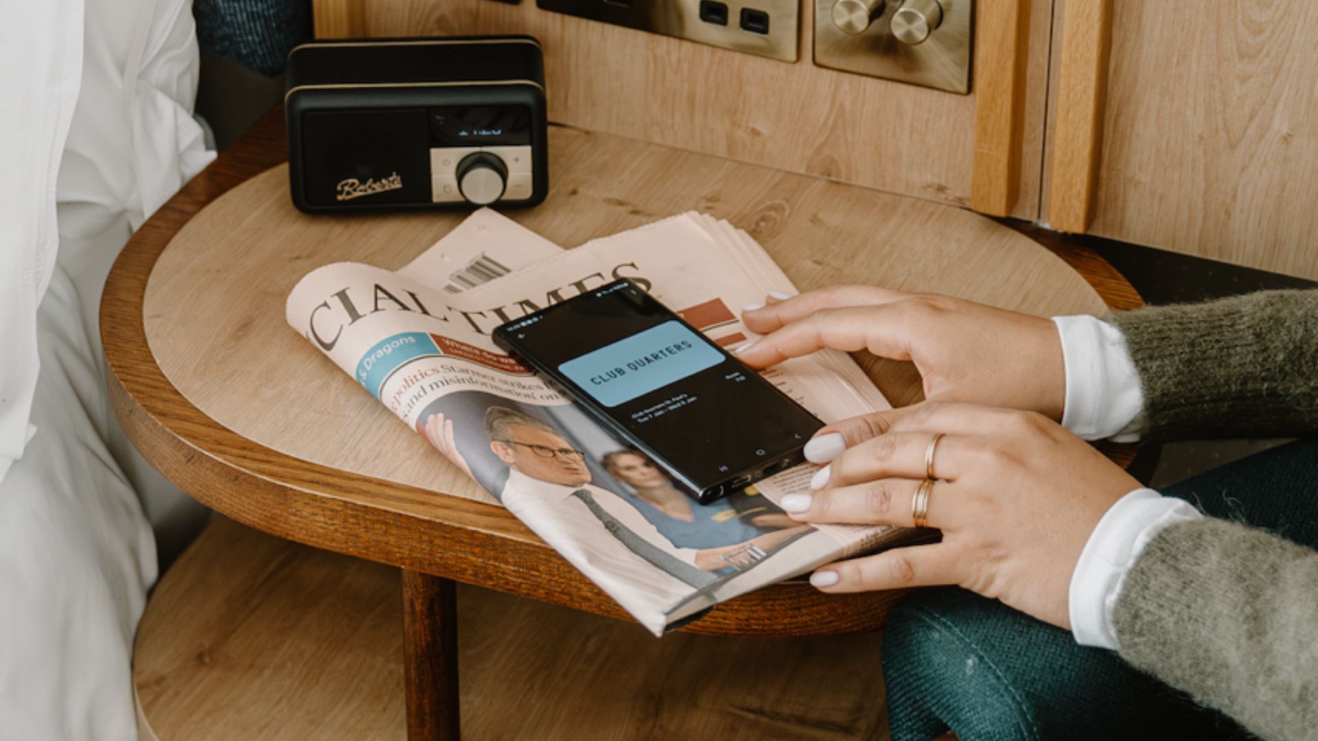 A phone showing a digital hotel room key sitting on a bedside table