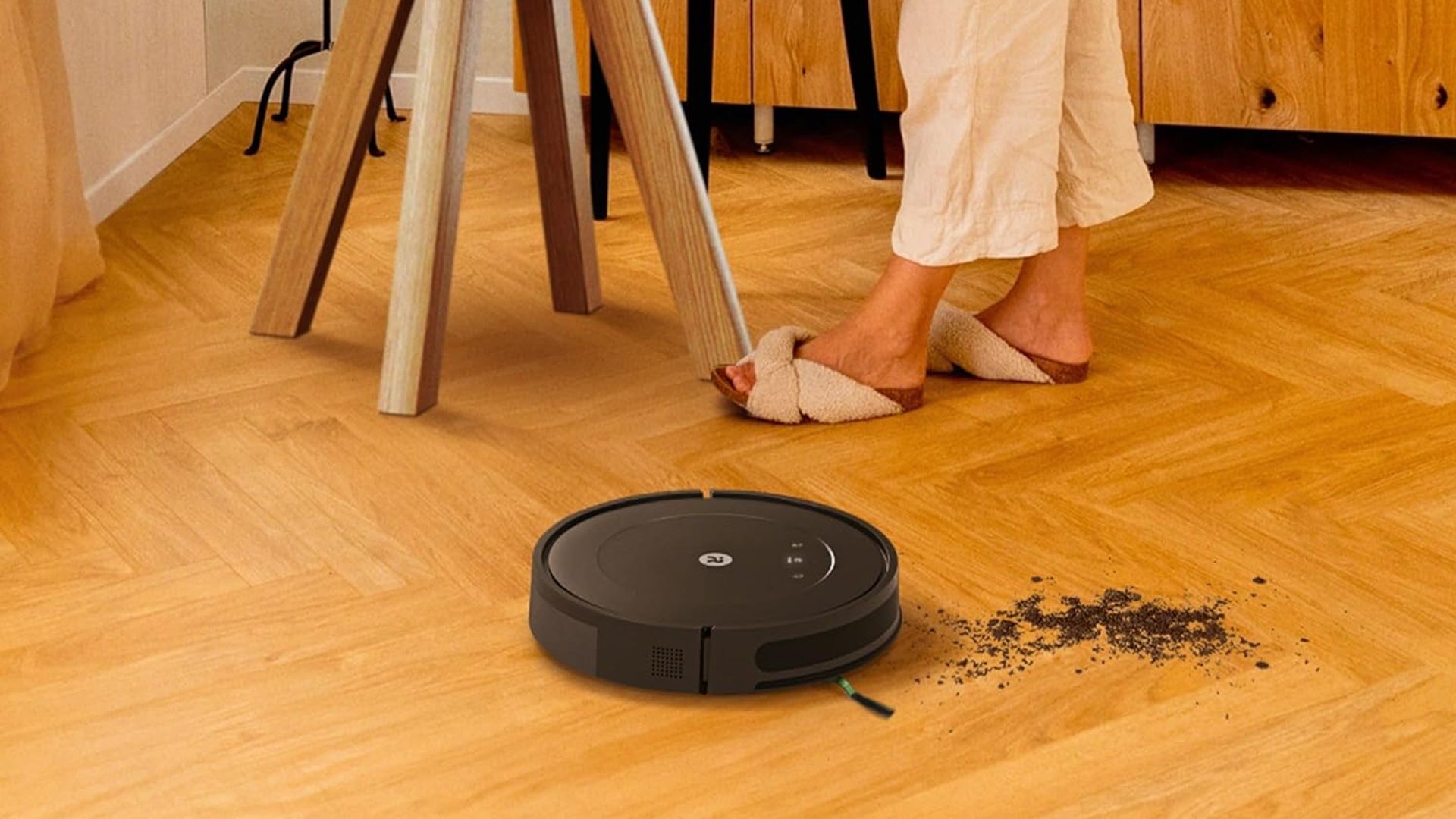 An iRobot Roomba Essential Vac (Q0120) cleans a hardwood floor.