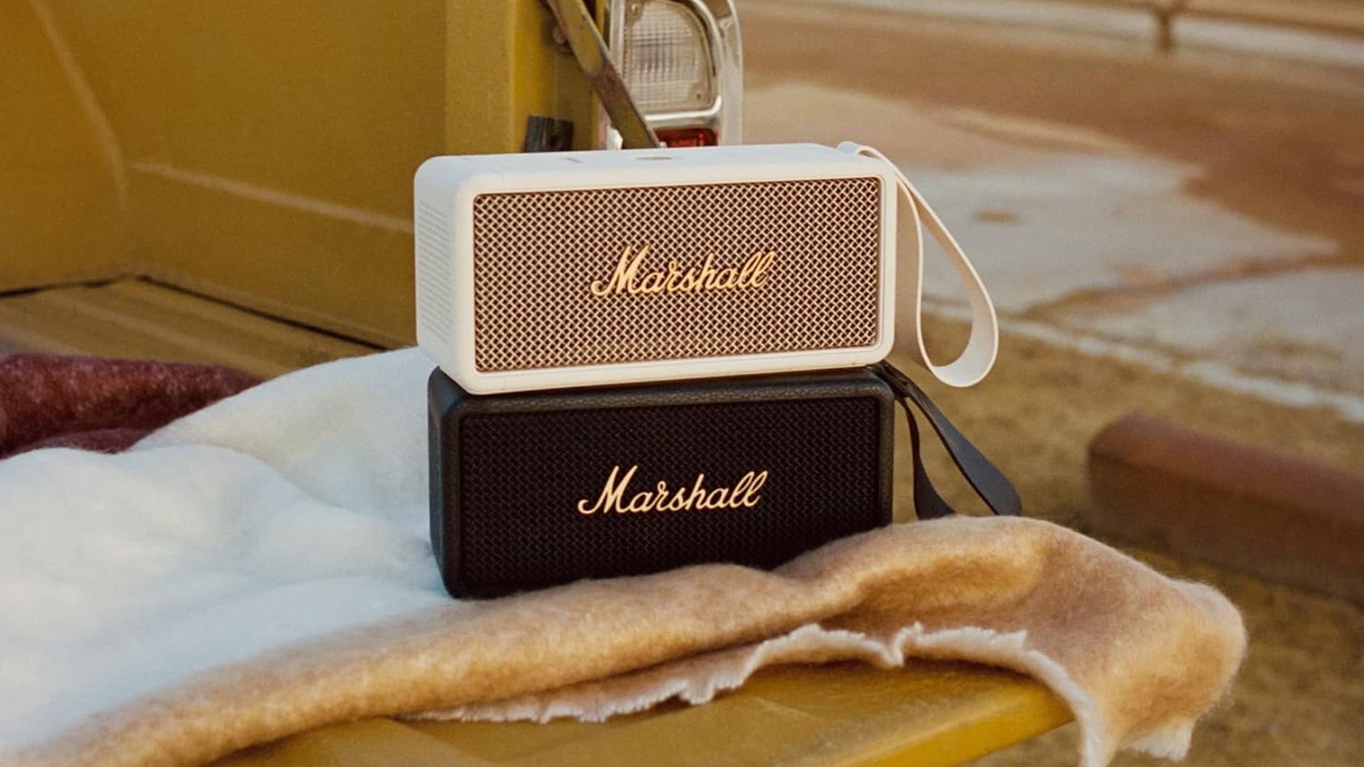 A white Marshall Middleton Bluetooth speaker stacked on top of a black Marshall Middleton.