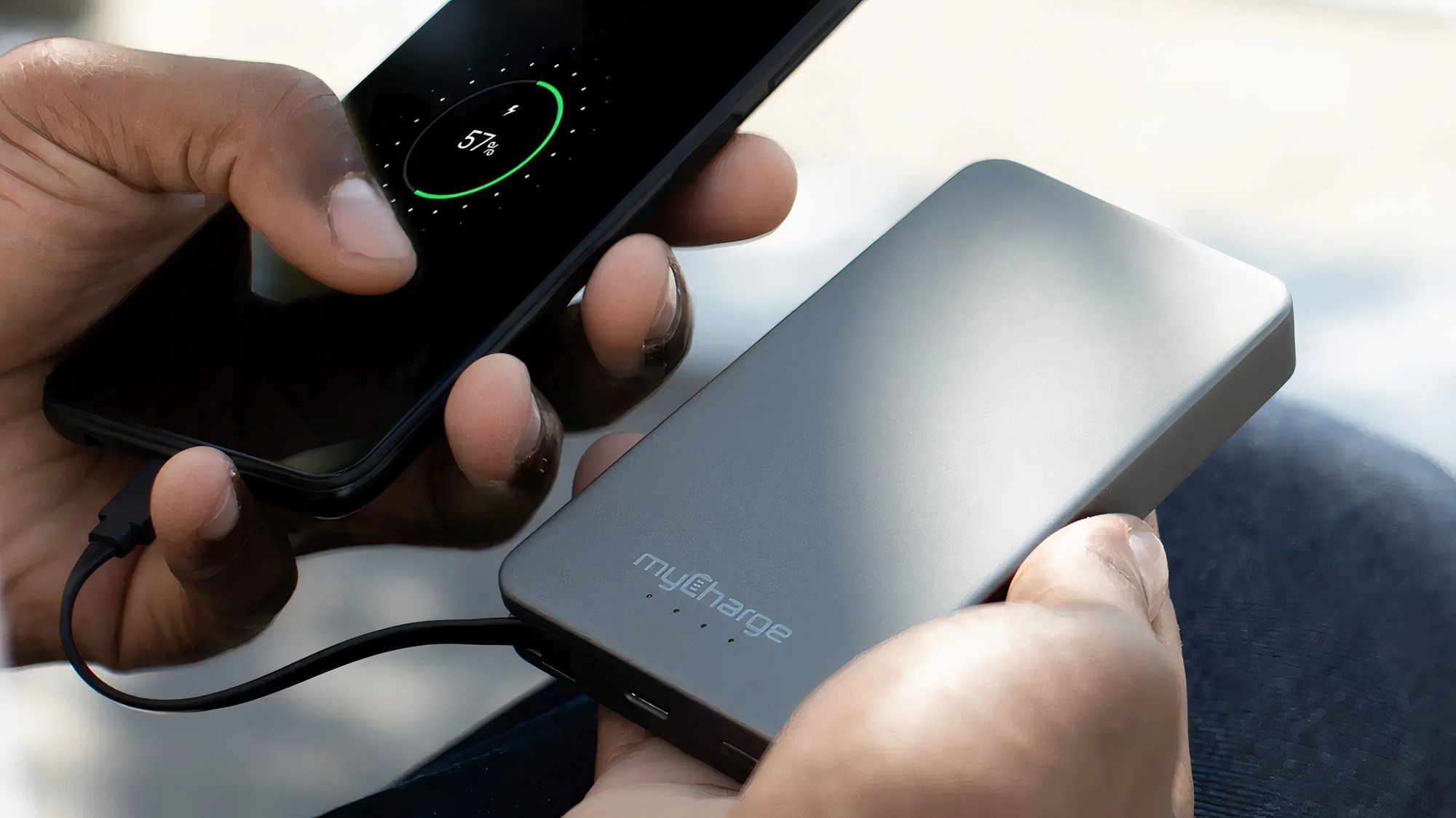 MyCharge AMP Prong 5K lifestyle shot showing device held in hand connected to phone