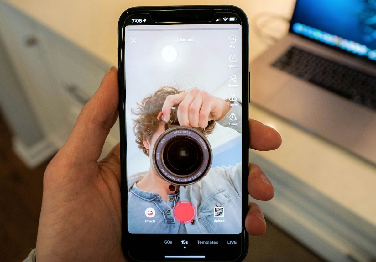 Hand holding phone with recording screen open on TikTok
