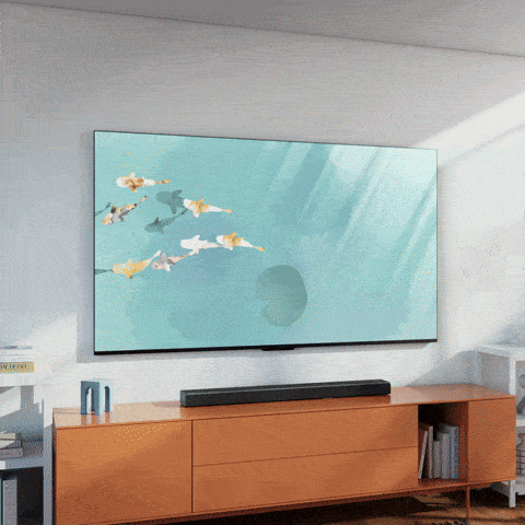 A gif of a Fire TV with a school of koi fish on the screen following a man around as he walks back and forth in front of it. 