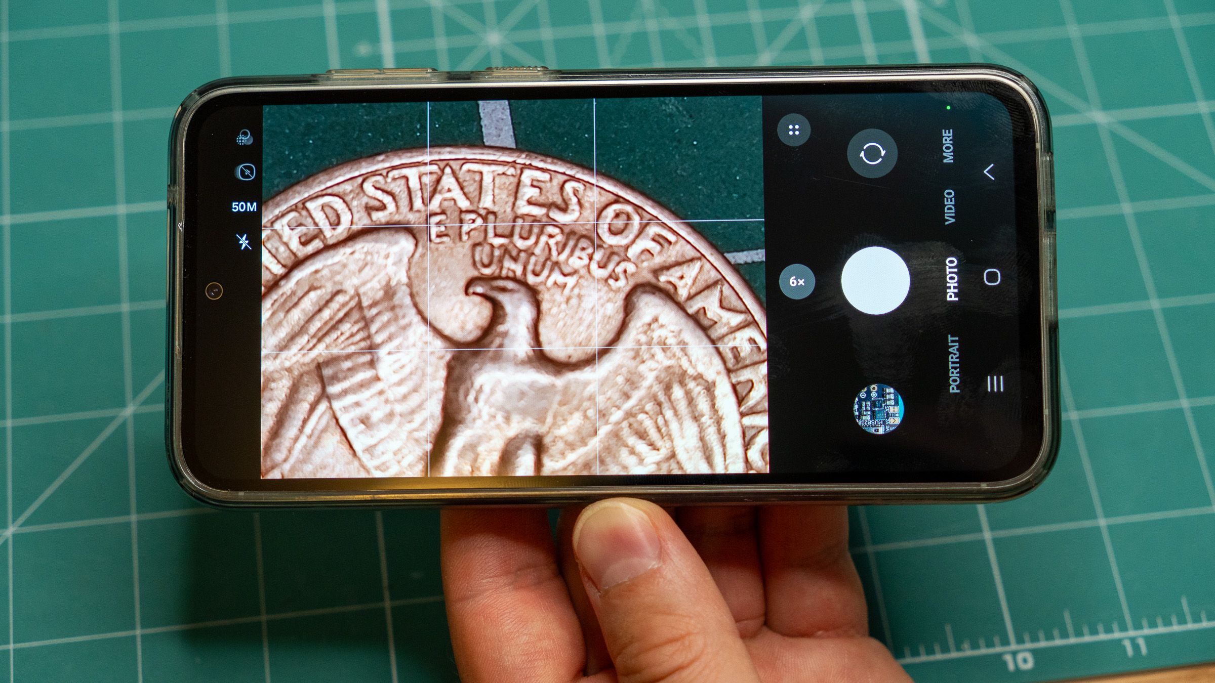 a phone in hand taking a close-up photo of a quarter dollar coin
