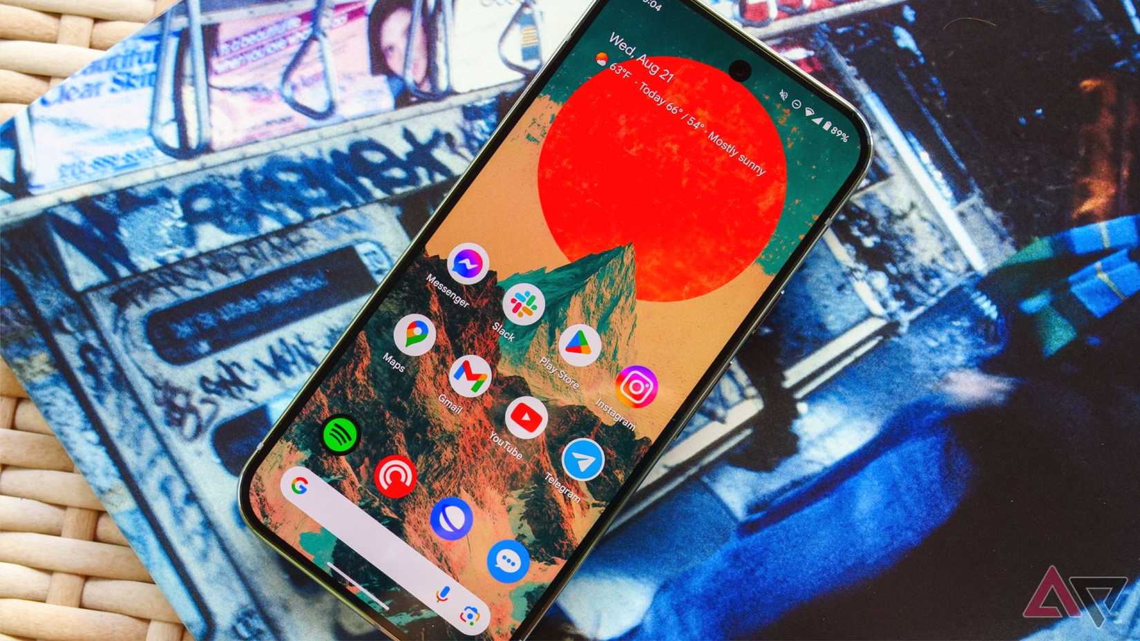 O Pixel 9 Pro em uma mesa de vime e deitado em um shell de álbum com a tela
