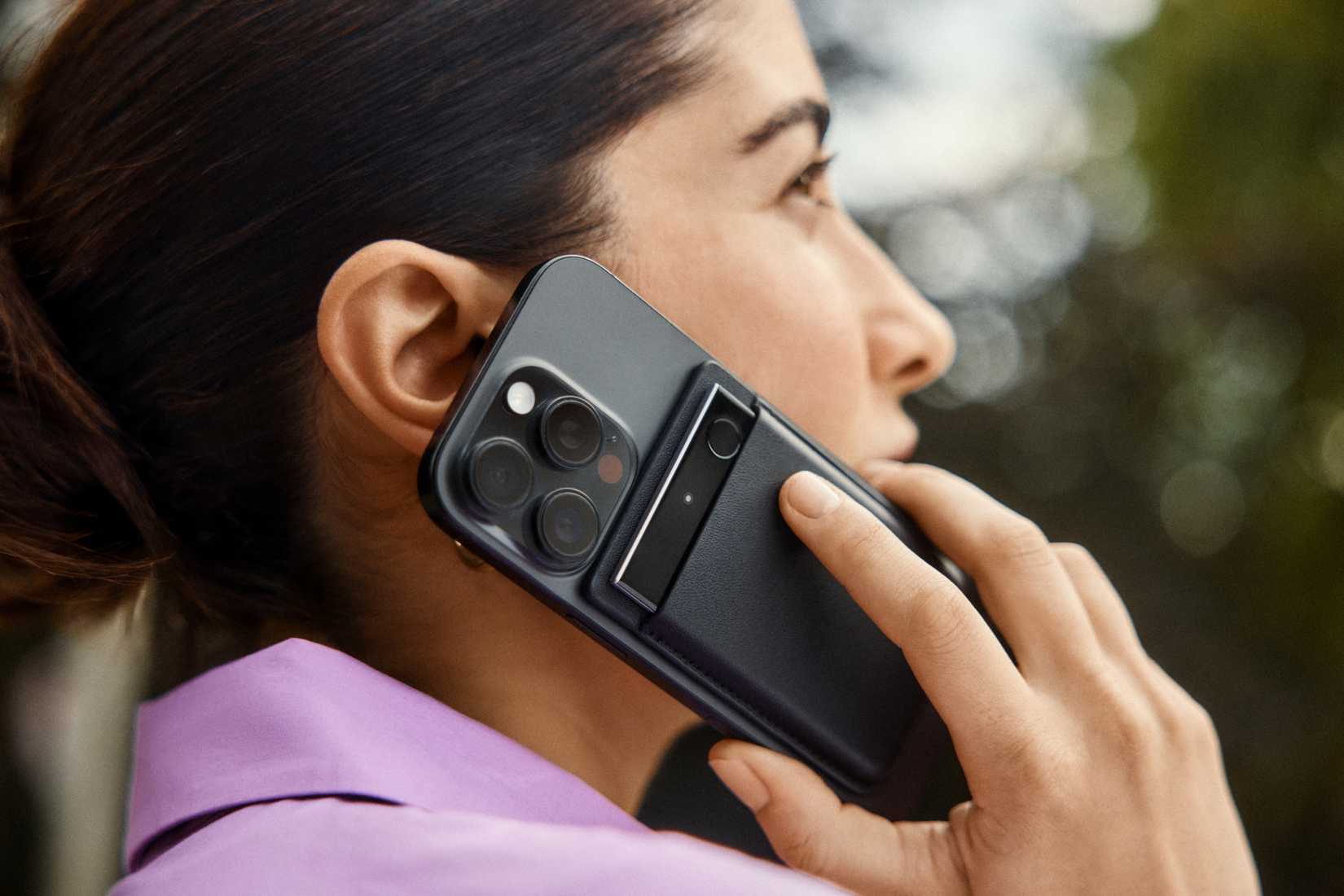 A woman talking on the phone with the Plaud Note Pro attached to her device.
