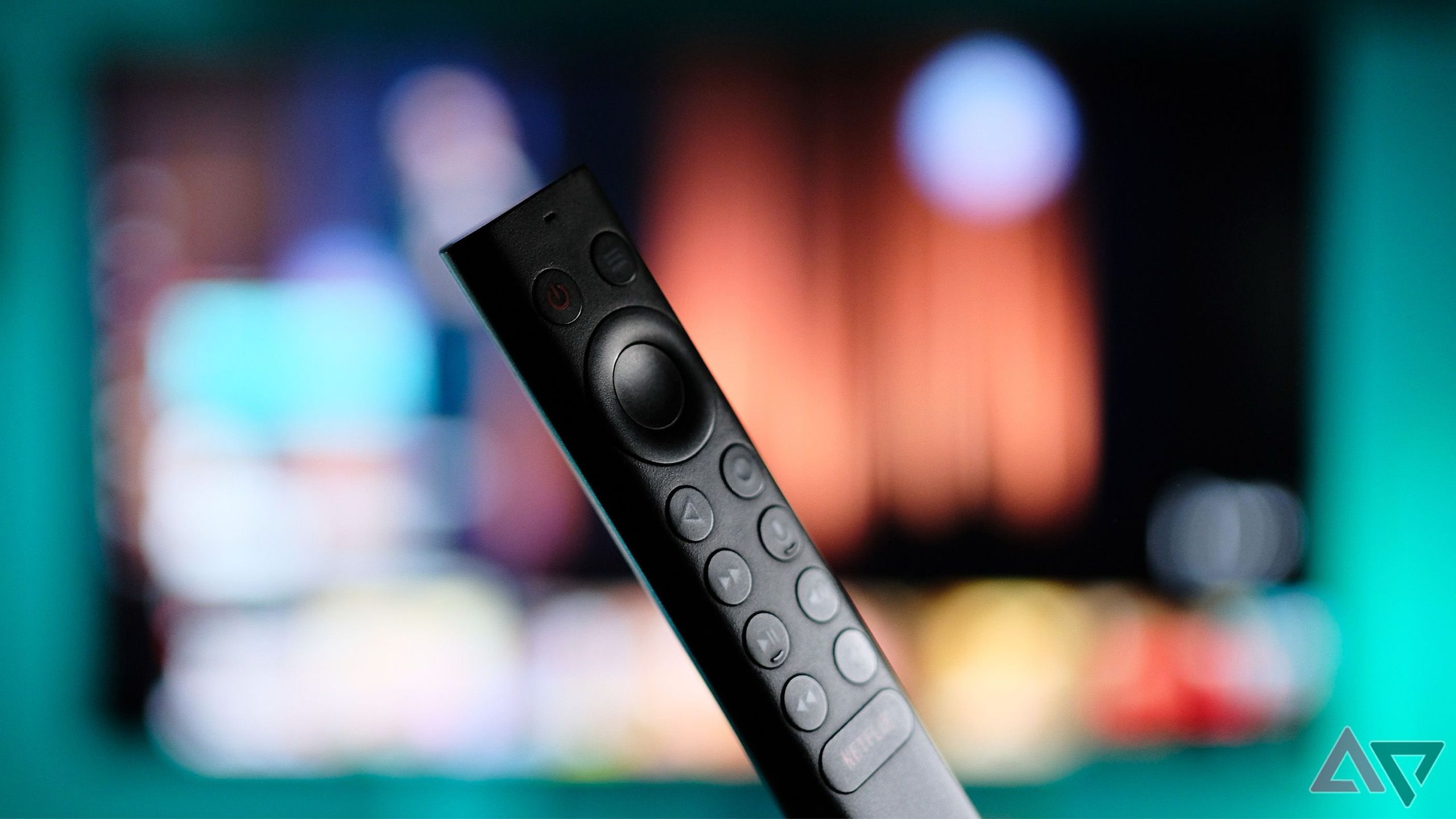Closeup of a black smart tv remote with TV in the background