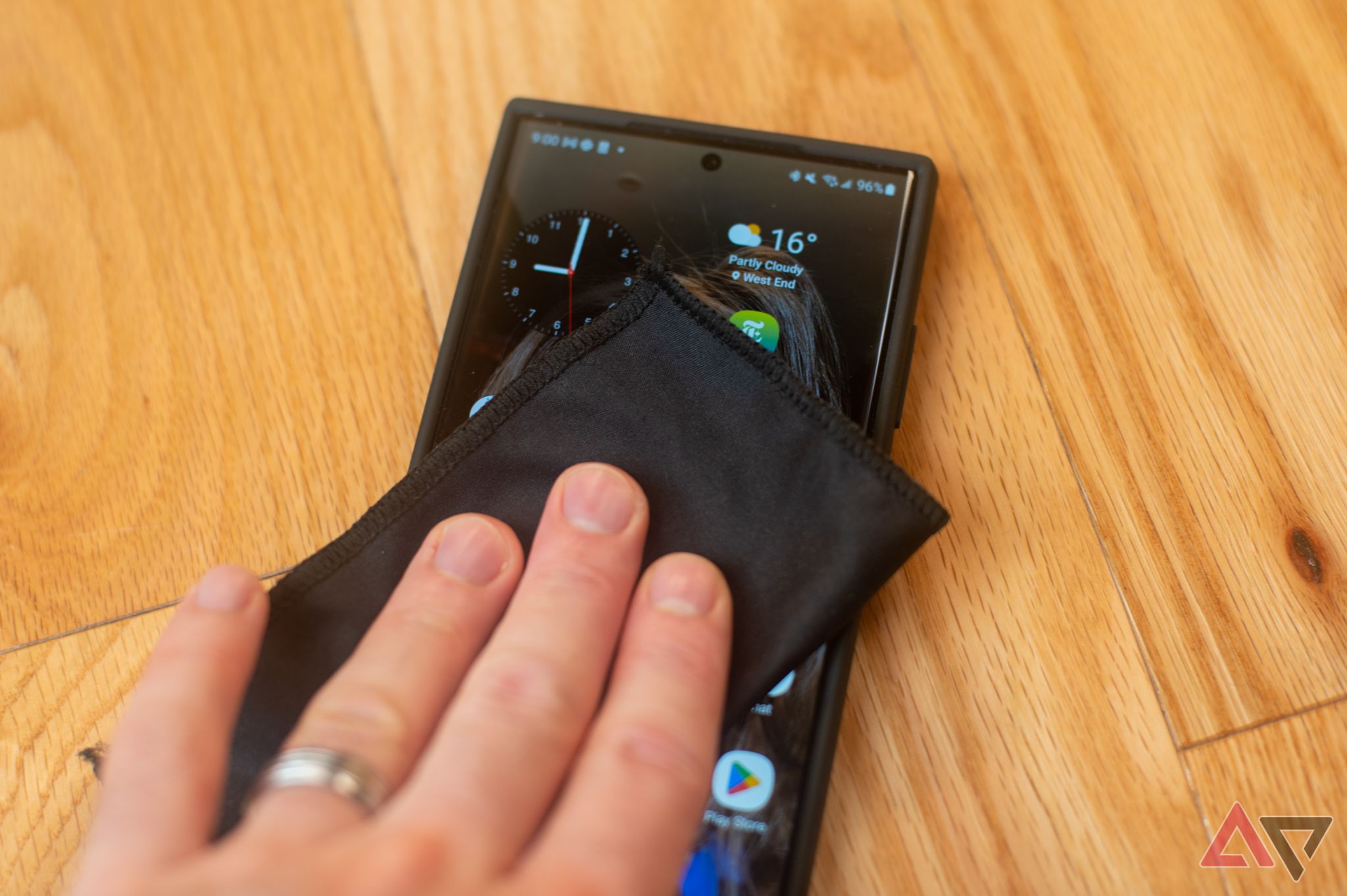 A hand cleaning a phone's body with a microfiber cloth