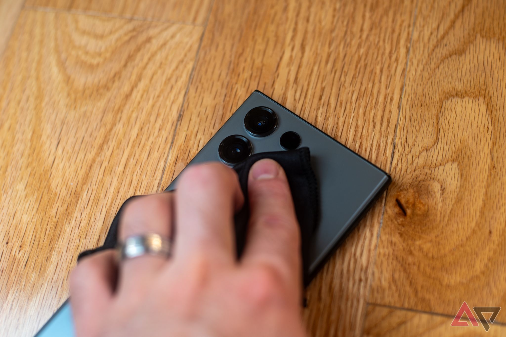 A hand wiping down the back of a phone with a microfiber cloth