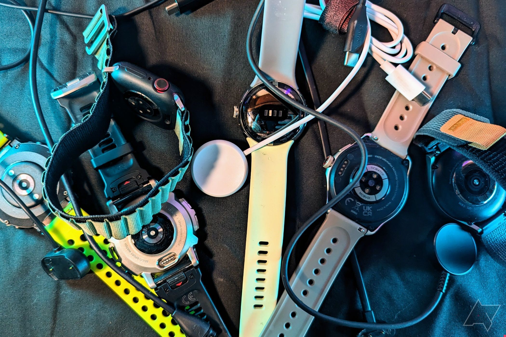 Apple Watch Series 7, Google Pixel Watch, Galaxy Watch 5 Pro, and TicWatch Pro 5 together with charging cables