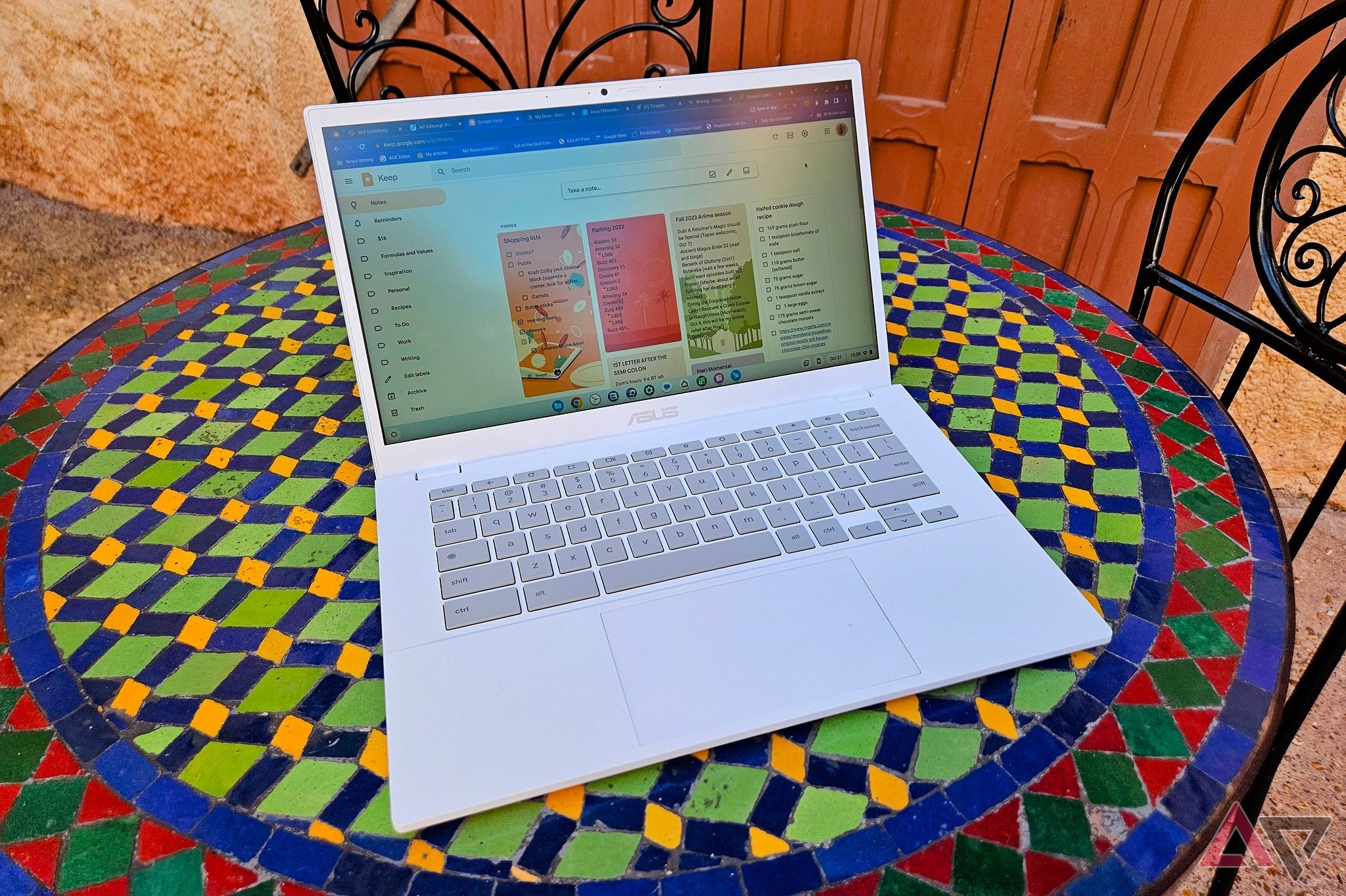 An Asus Chromebook Plus CX34 sitting on a colorful mosaic table outdoors.