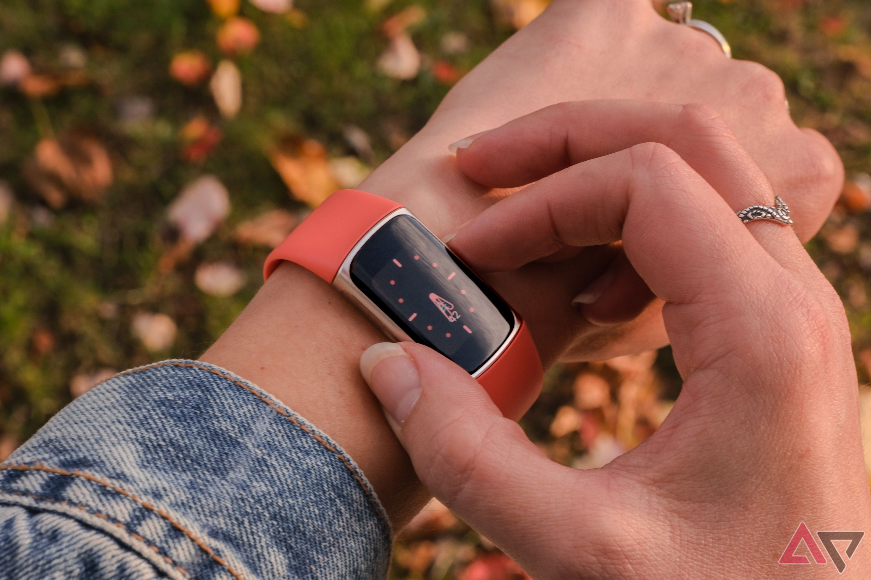 A Fitbit Charge 6 with an orange band and worn on a wrist