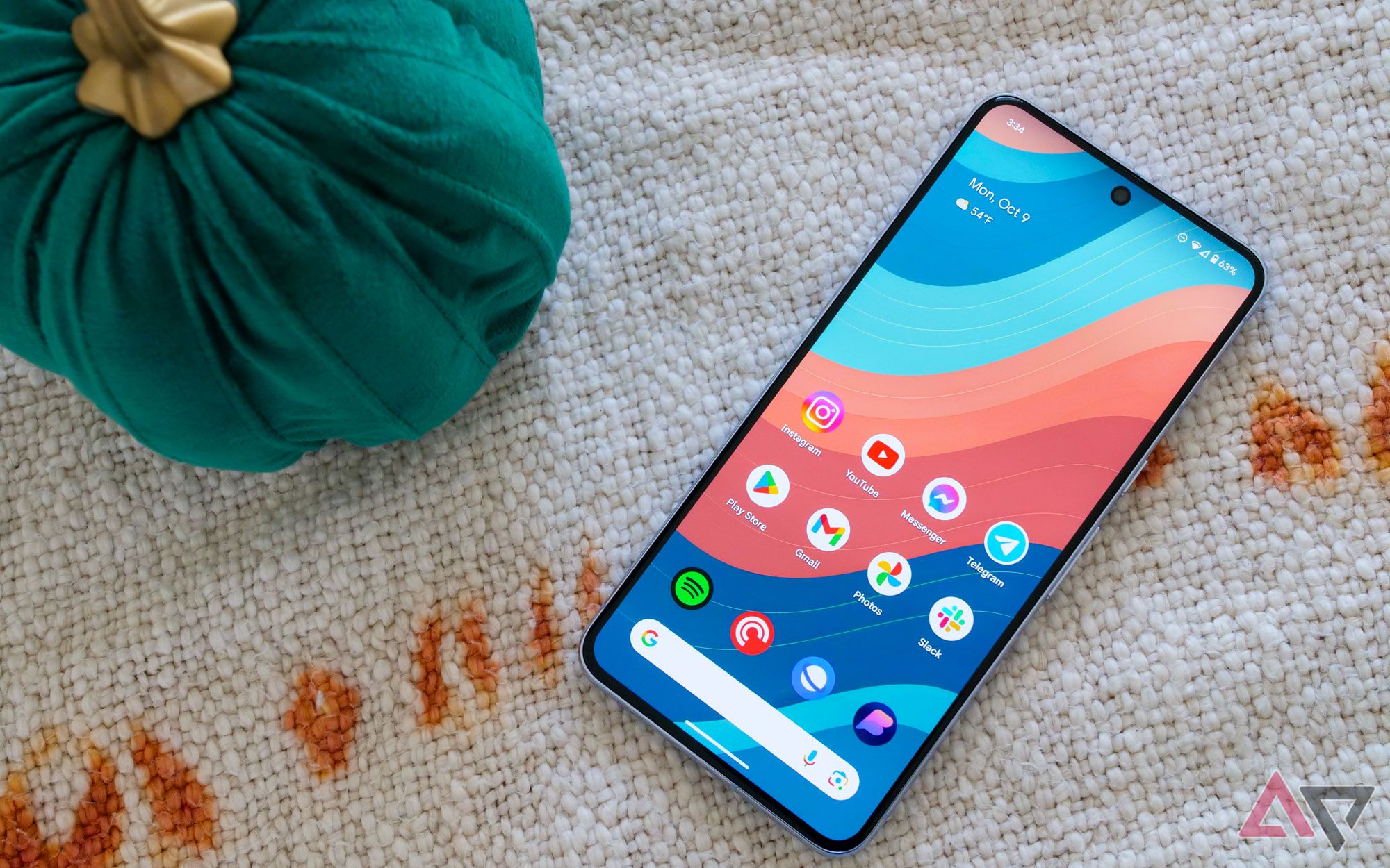 A Google Pixel 8 Pro smartphone sitting on a canvas cloth next to a green pumpkin.