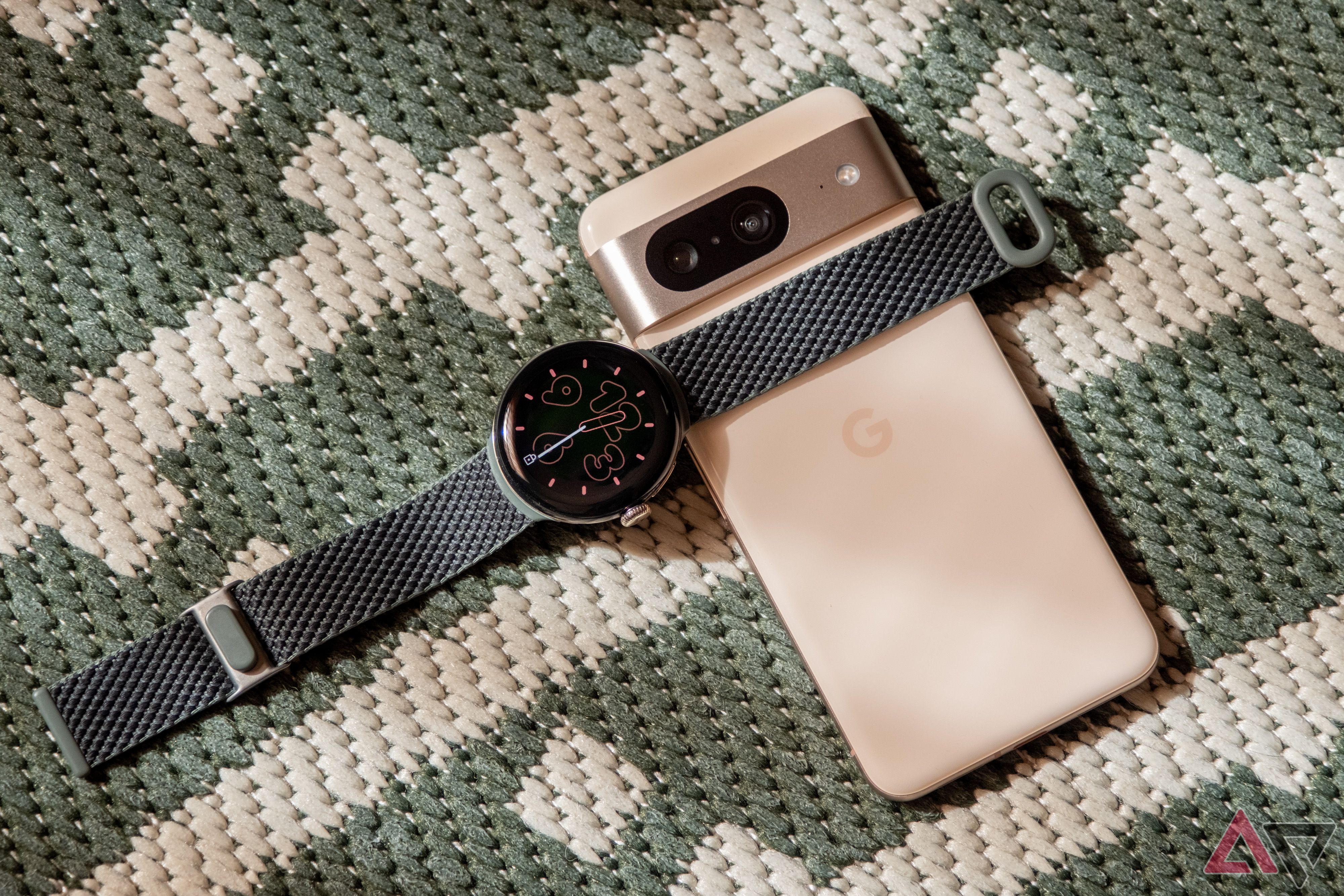 A Google Pixel Watch 2 rests atop a Pixel 8 phone