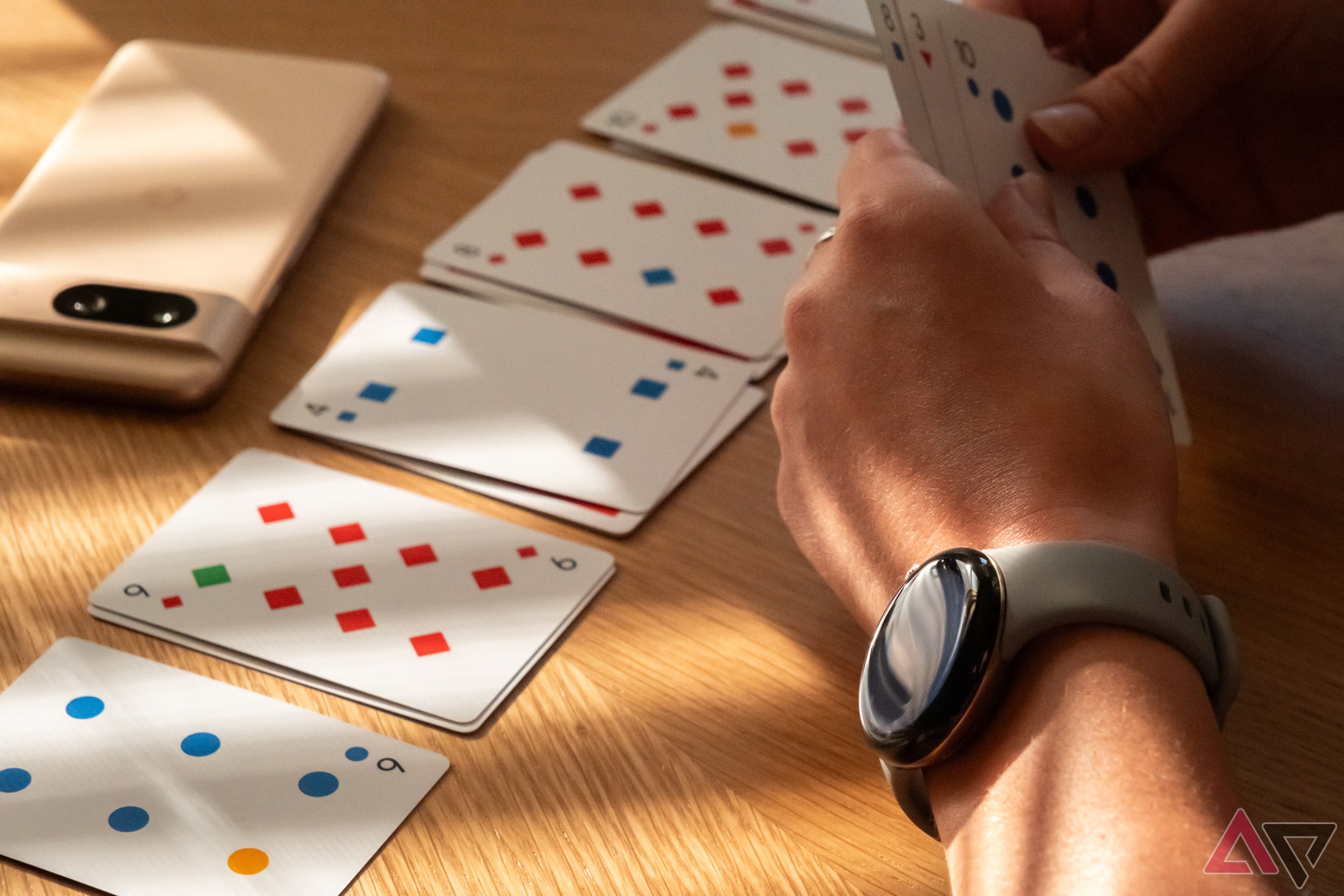 A person wear a Google Pixel Watch 2 while playing cards.