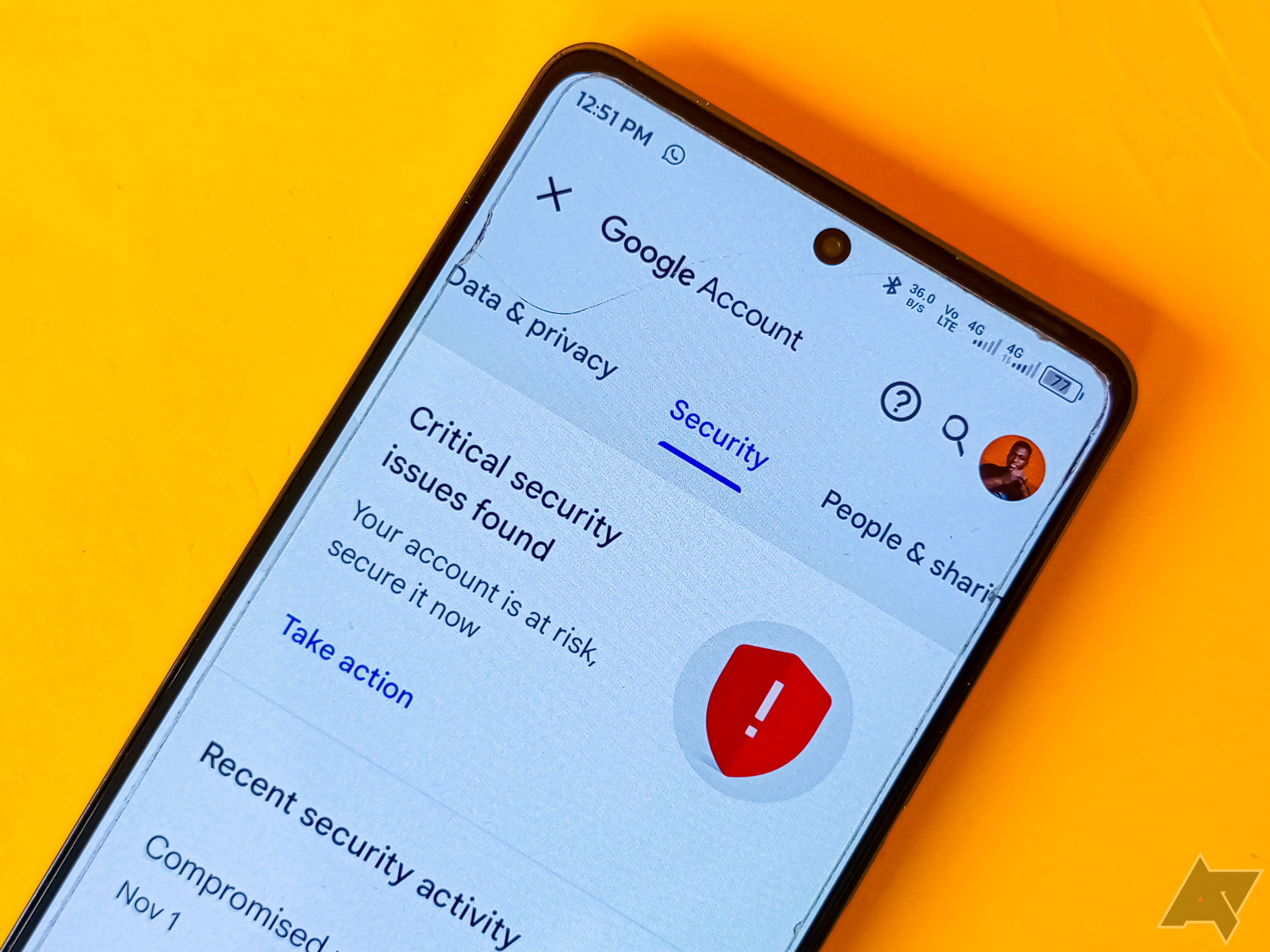 The Google account security settings screen captured on a phone placed on a yellow background. 