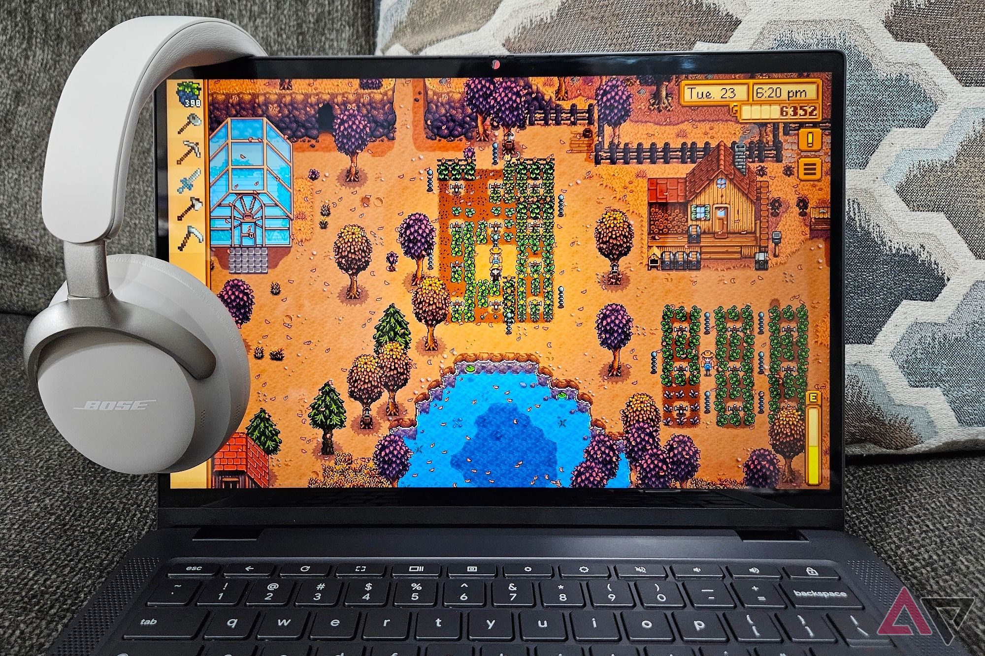 A Lenovo Chromebook Plus Flex 5i playing Stardew Valley with a pair of Bose QuietComfort Ultra hanging on the edge of the screen