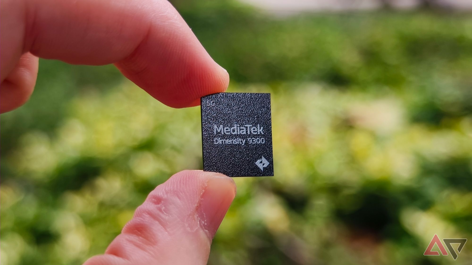 MediaTek Dimensity 9300 chip logo side held in front of a green park