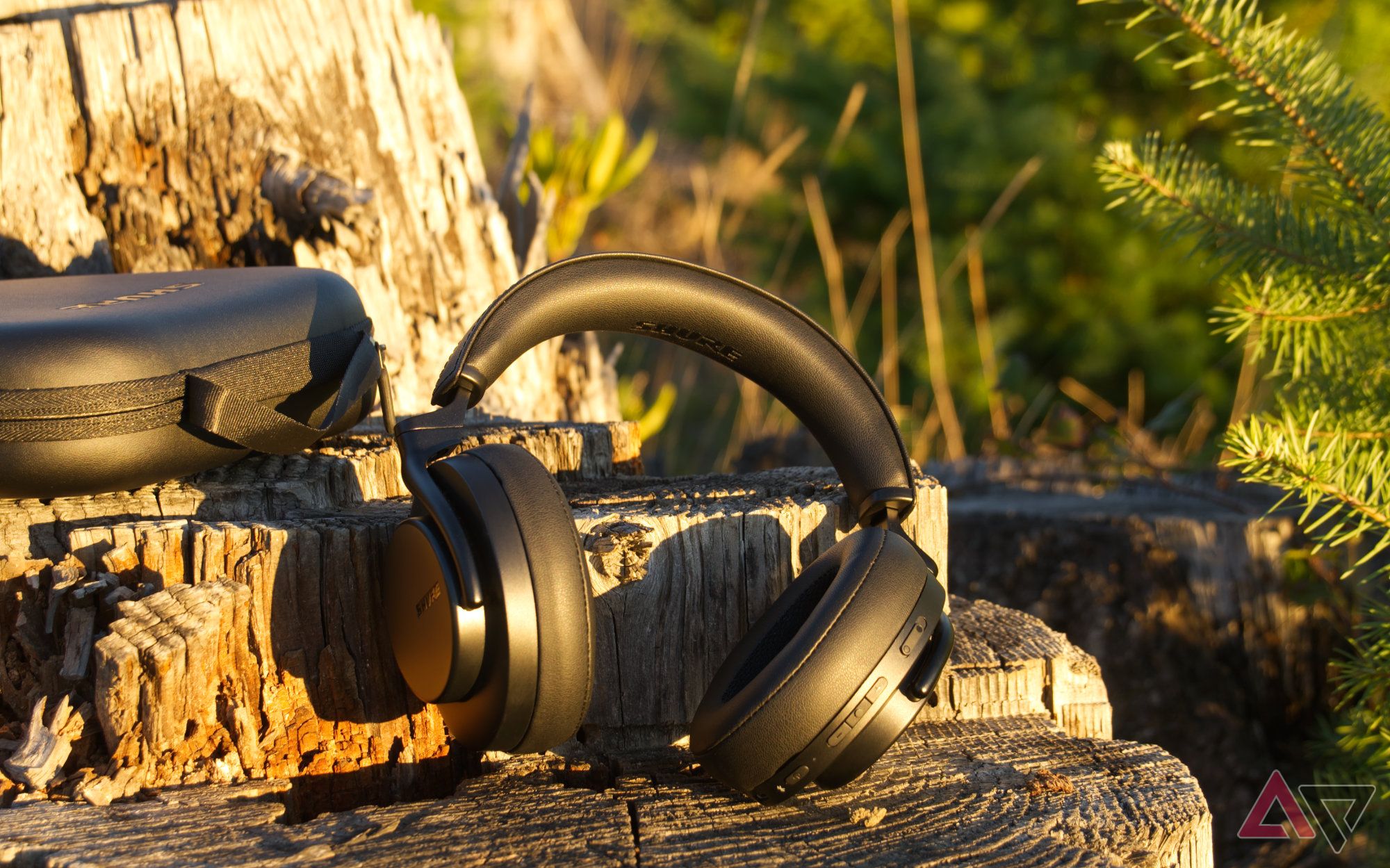 Shure Aonic 50 Gen 2 headphones and case sitting on a stump